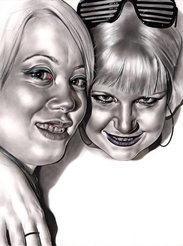 Black and white photograph of two women close together, smiling and looking at the camera. One has short hair with sunglasses on her head, and the other has longer hair.