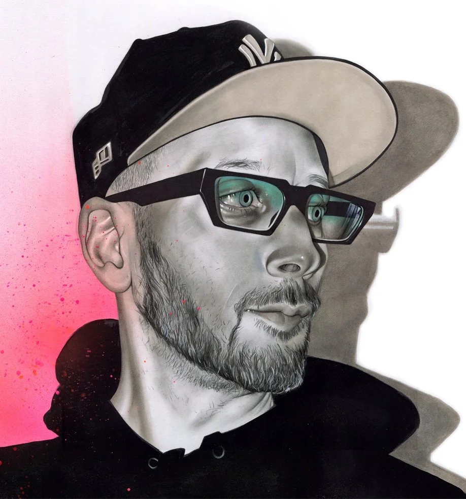 Detailed street art mural of a man wearing glasses, a baseball cap, and a hoodie, with a realistic style, featuring pink spray paint splatters on the side.