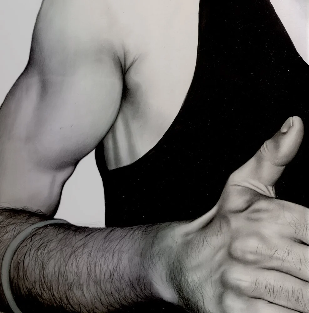 Close-up of a person's shoulder, arm, and hand in black and white, with the arm bent at the elbow and the hand extended.
