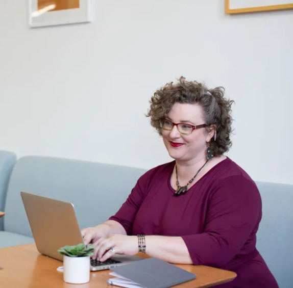 woman working on laptop while smiling at screen