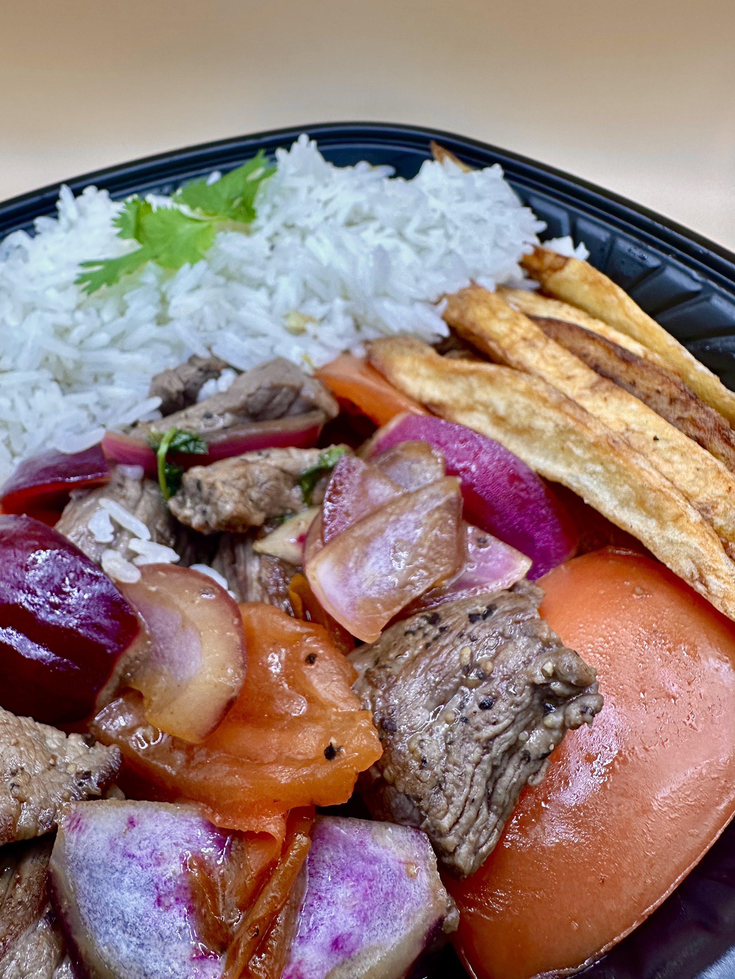 Lomo Saltado - Sautéed steak with tomatoes, onions, tomatoes, cilantro, Ahi Amarillo with rice and fries