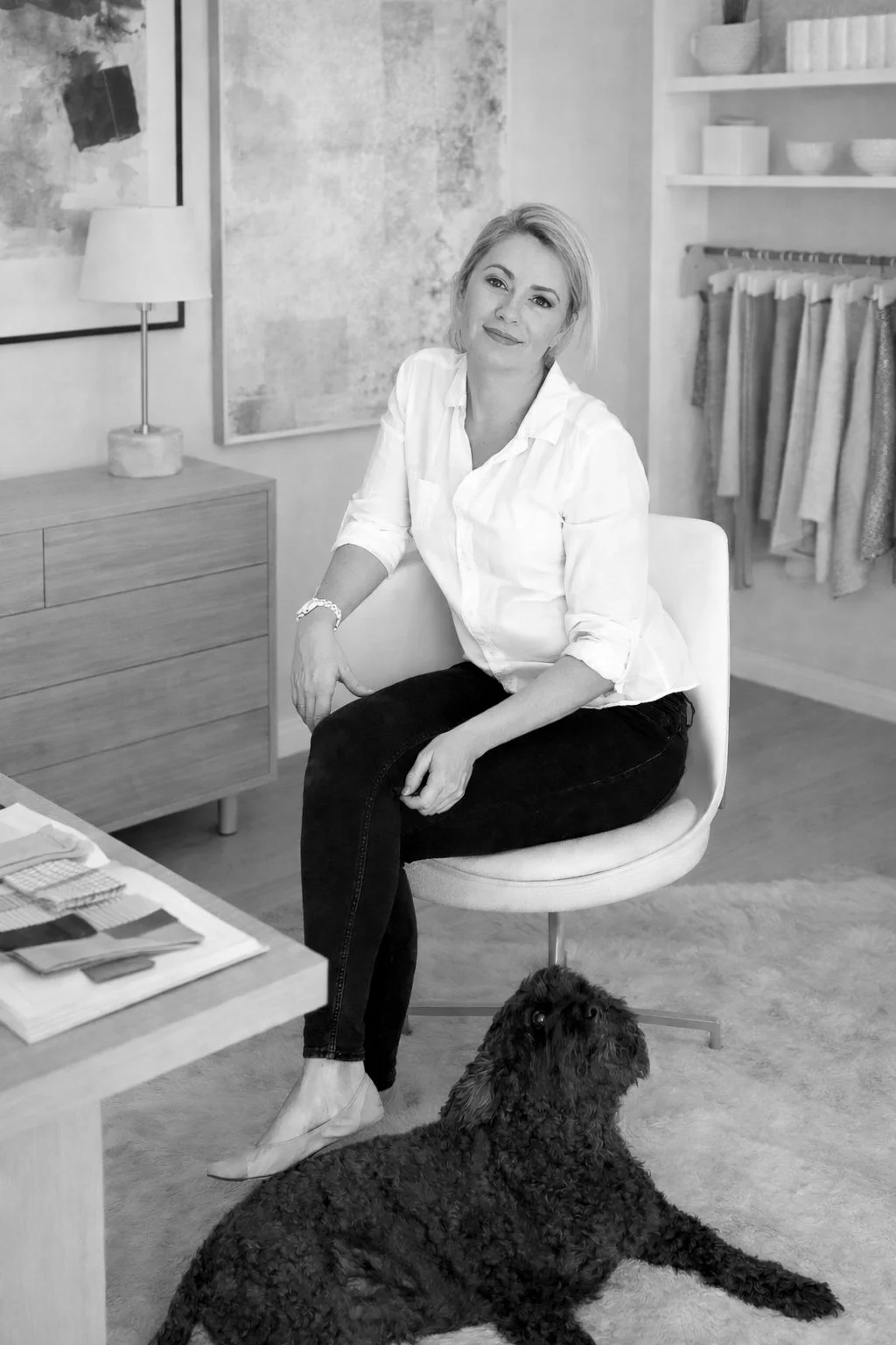 Lauren Daly, interior designer, seated in her design studio surrounded by neutral fabrics and materials