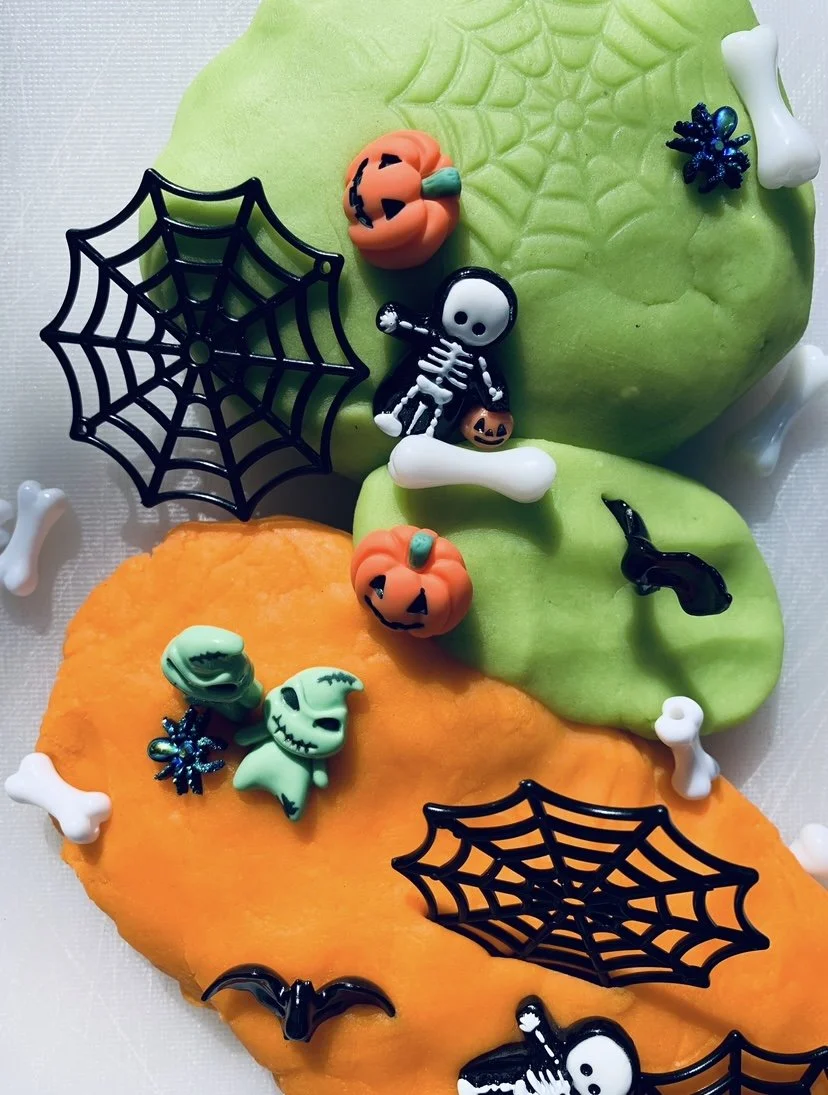 Halloween-themed dough decorated with orange and green , featuring spiderwebs, skeletons, pumpkins, bats, skulls, black cats, and bones.