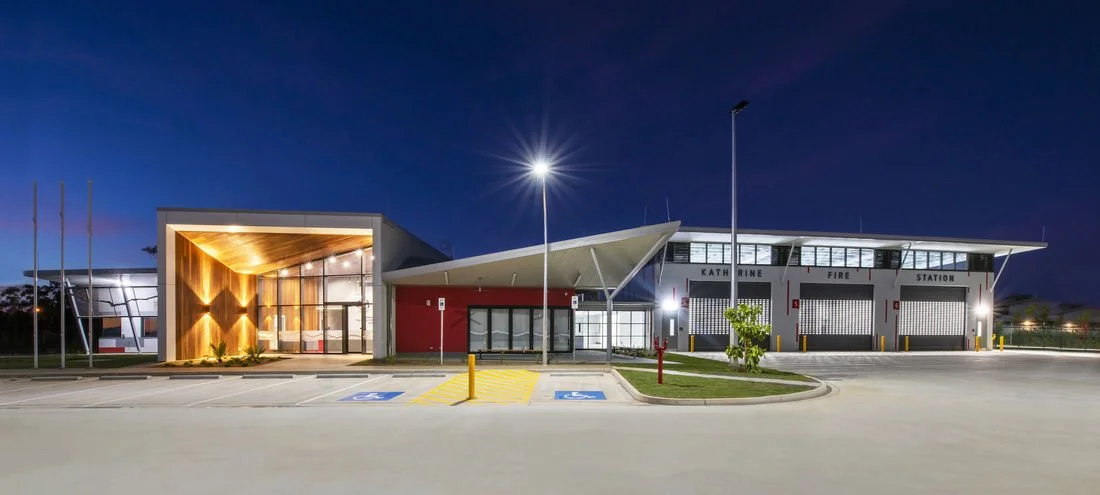 Night view of a modern fire station with an ambulance parking area in front.