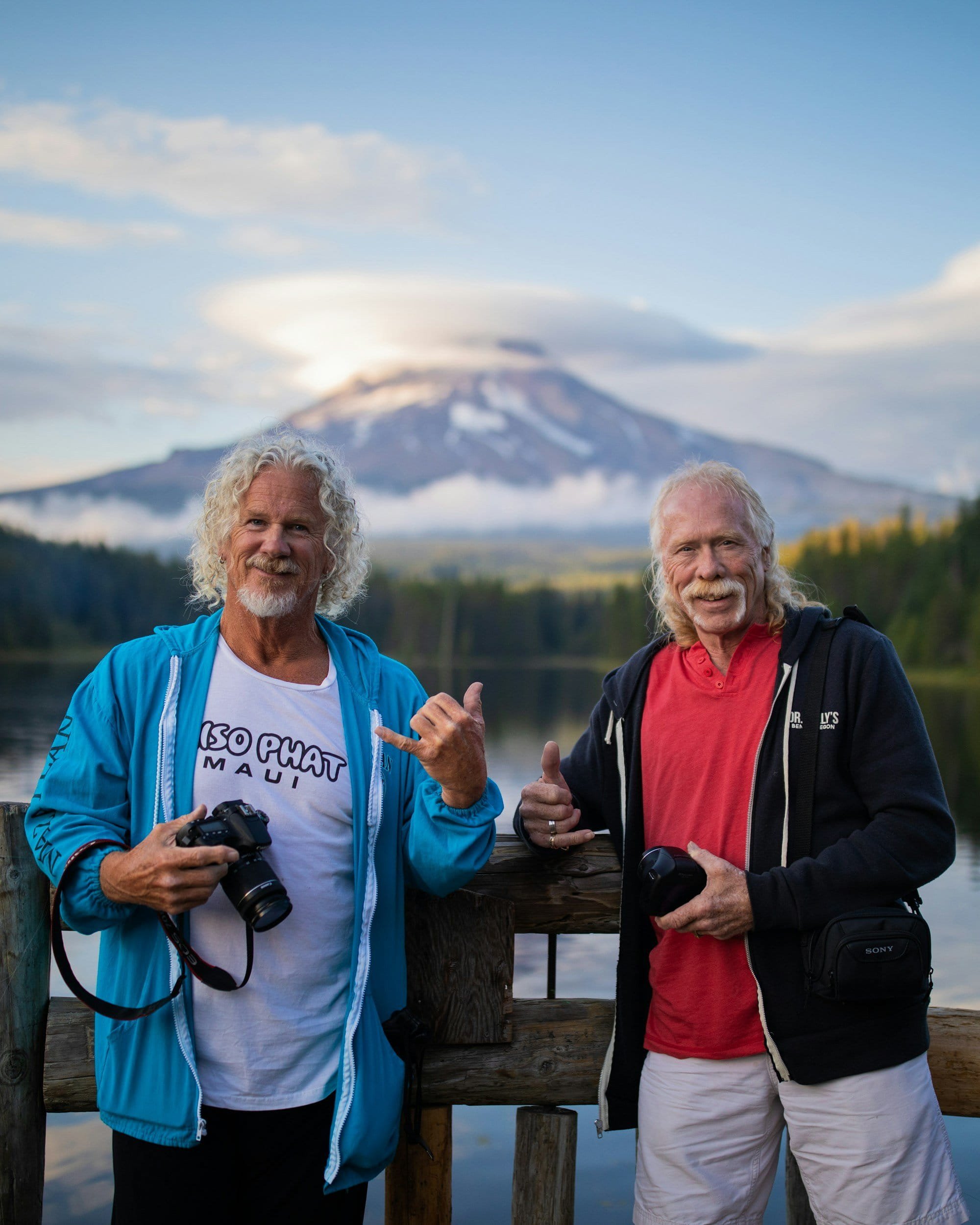 Two old man posing for a photo in front of a beautiful view.