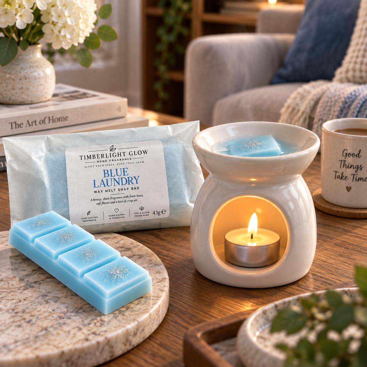 Blue Laundry wax melt snap bar beside a lit ceramic wax burner in a cosy home setting.