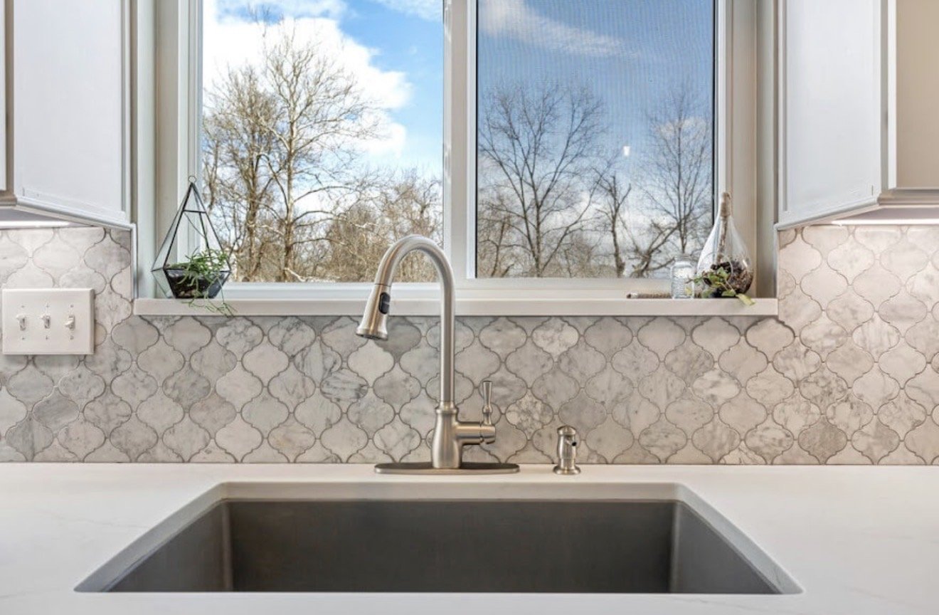 Kitchen sink with faucet window view of trees and sky.