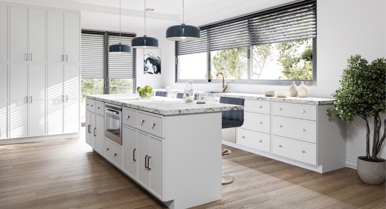Modern kitchen with white cabinets, marbled countertops, and large windows with blinds, featuring a kitchen island with a built-in oven, blue leather chairs, pendant lighting, and a potted plant.