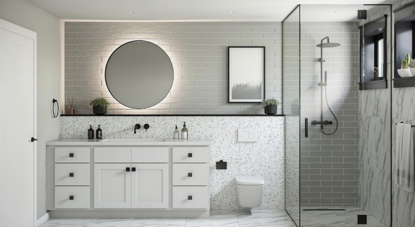 Modern bathroom with white vanity, black hardware, circular mirror, gray brick wall, framed artwork, potted plants, and walk-in shower with glass enclosure and gray tiles.