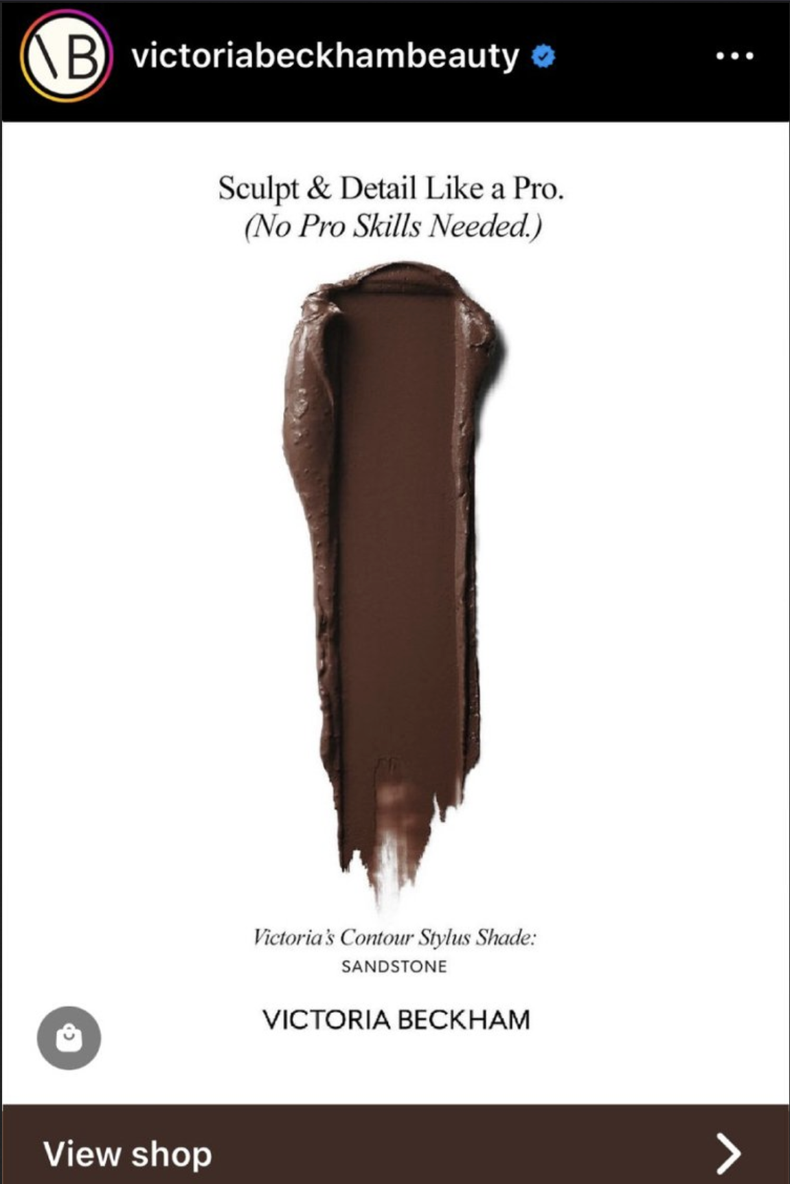 An advertisement for Victoria Beckham's beauty products featuring a brown makeup shade called 'Sandstone,' with a smear of the lipstick or eyeshadow in the center of the image. The text says, 'Sculpt & Detail Like a Pro. (No Pro Skills Needed.)' and 'Victoria's Contour Stylus Shade: SANDSTONE. VICTORIA BECKHAM.' at the bottom.