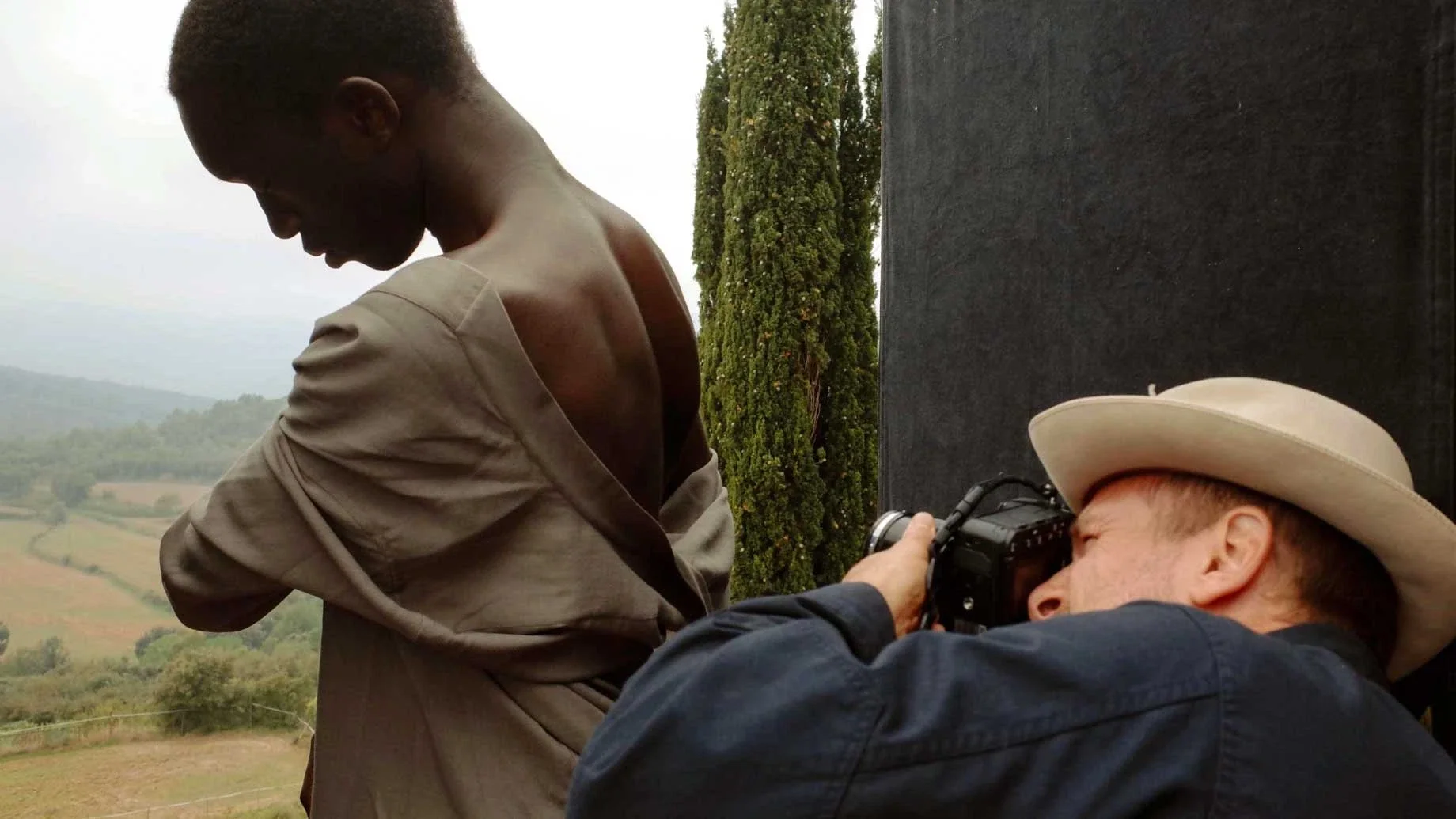 A photographer taking a close-up shot of a woman with a scenic landscape in the background.