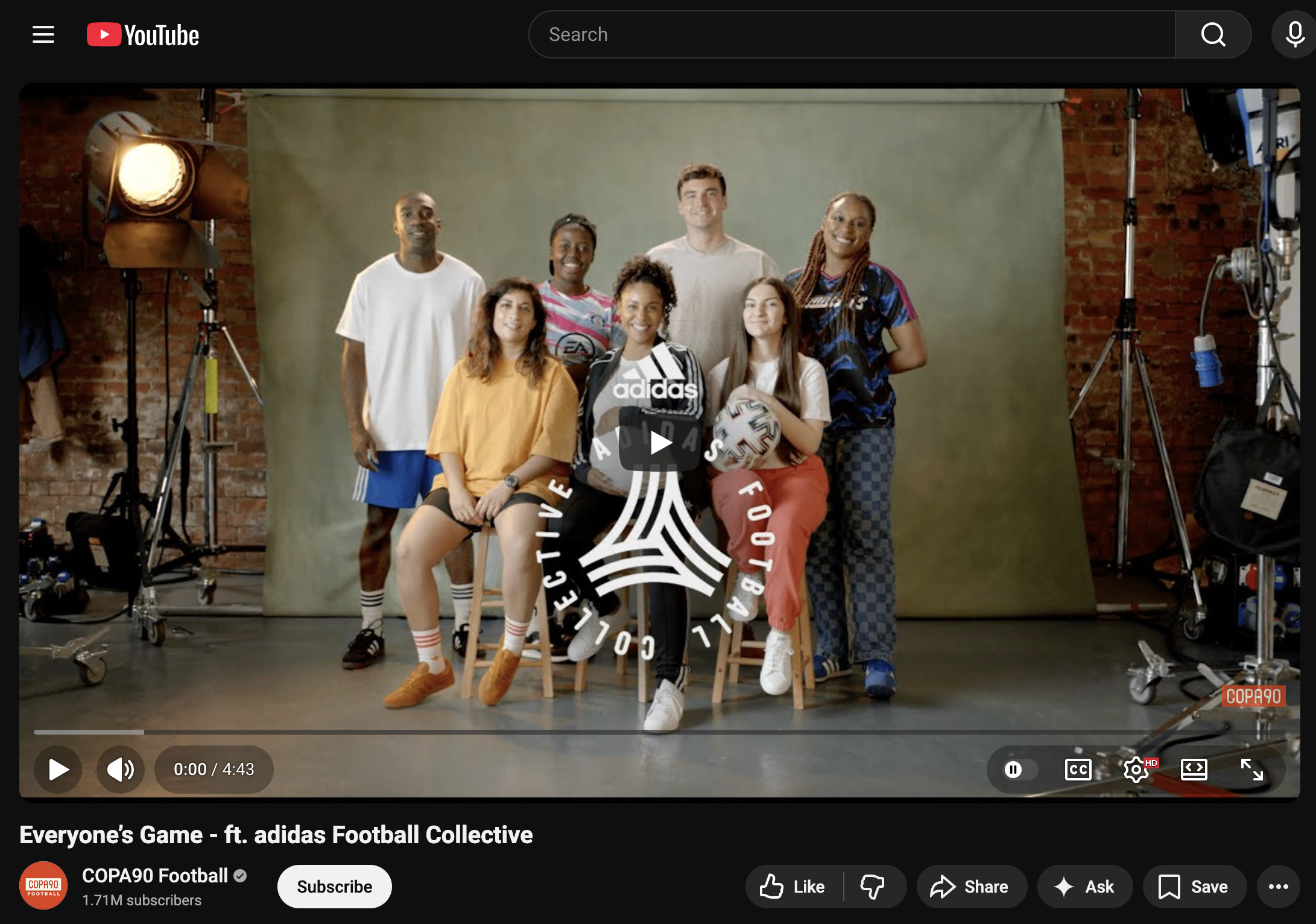 Group of seven diverse people posing together in a photography studio with camera lighting, against a plain green backdrop. Some are sitting, some standing, with the adidas logo and a graphic reading "adidas FOOTBALL COLLECTIVE" superimposed on the image.