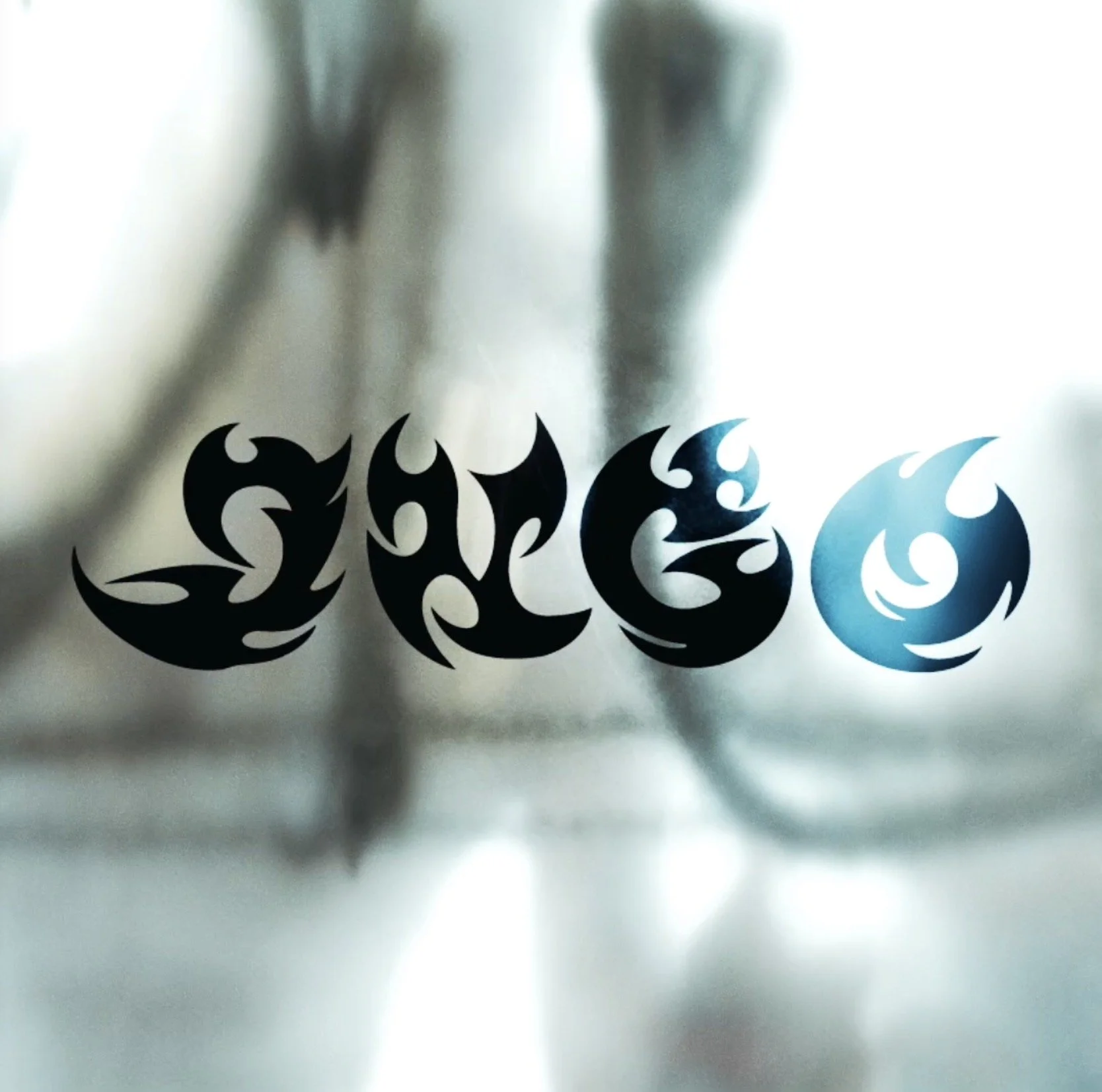 The word "Love" written in stylized black and blue tribal font on glass surface with blurred background.