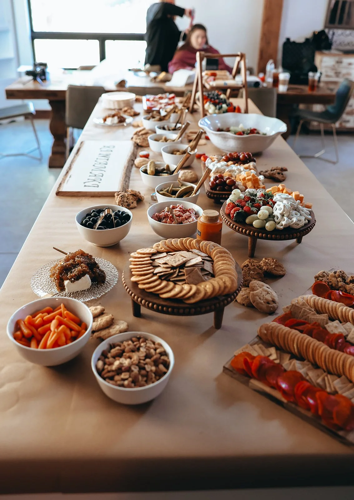 A long table with plates of cookies, snacks, chocolates, vegetables, and fruit, set for a gathering or celebration.