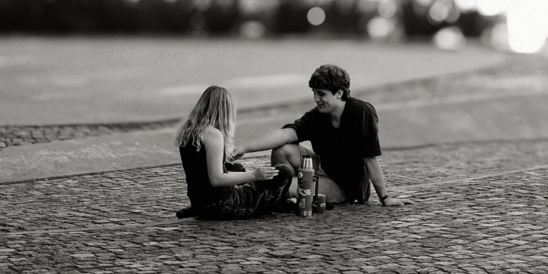 Couple sitting intimately together on cobblestone street in black and white — couples therapy Philadelphia, trust and relationship healing