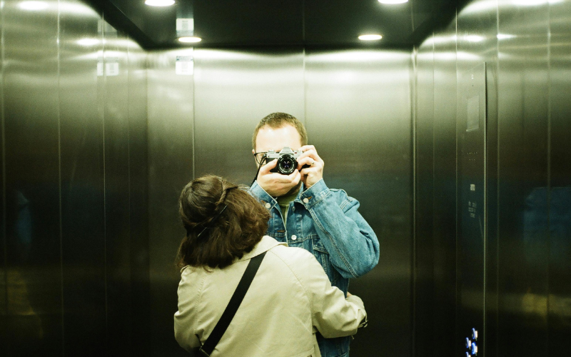 Person photographing their reflection in a gold elevator door — individual therapy for relationship issues and relational patterns, therapist Philadelphia
