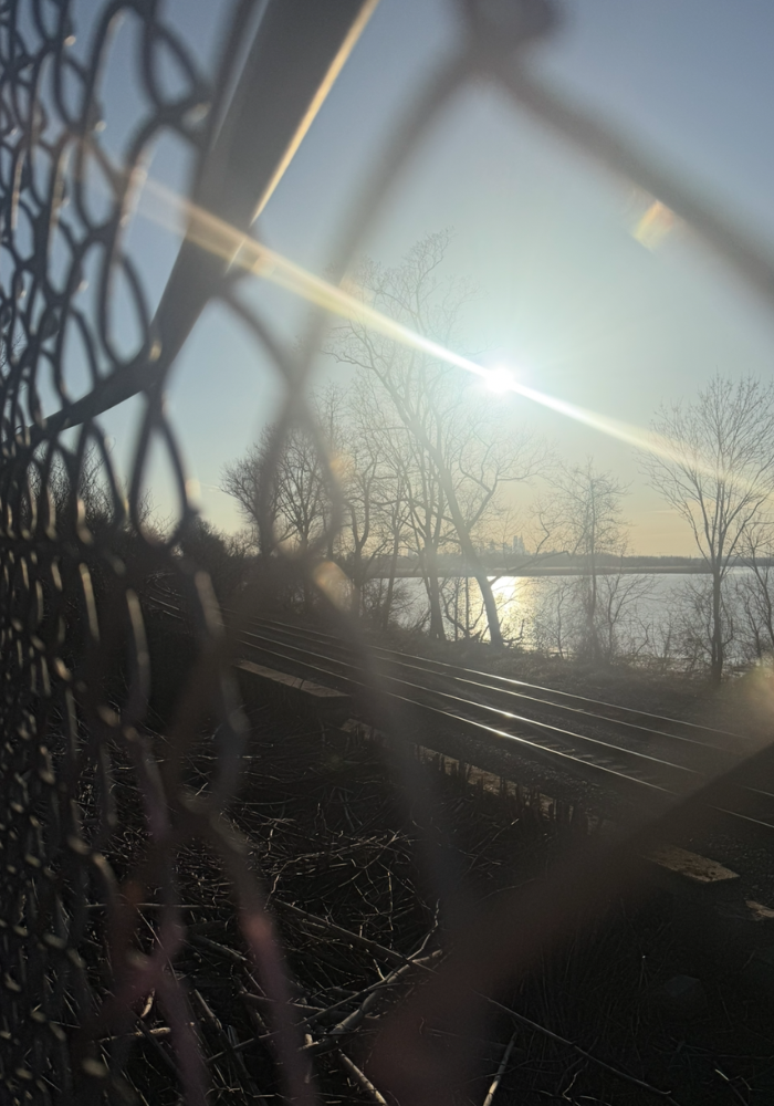 Sunlight streaming through a chain link fence over Philadelphia train tracks — depth-oriented therapist at The Relational Space serving PA and NJ