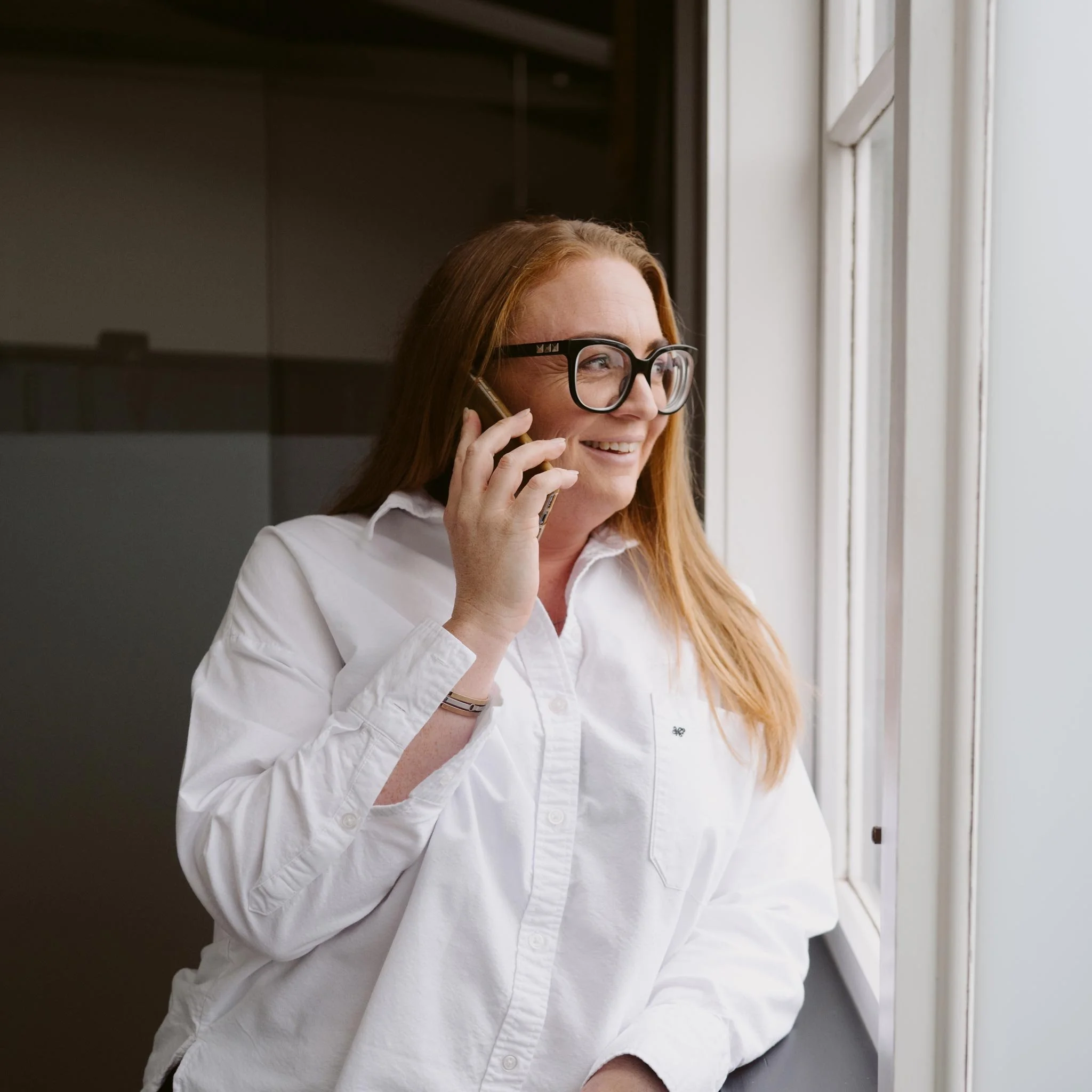 Aliesha Rowe smiling while talking on phone and looking out the window