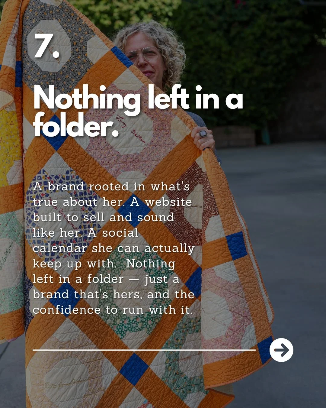 A woman holding a quilt made of various fabric squares with different patterns and colors, standing outdoors with trees in the background.