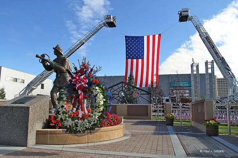 The Alaska Fallen Firefighter Memorial in Anchorage with an American flag and floral tributes