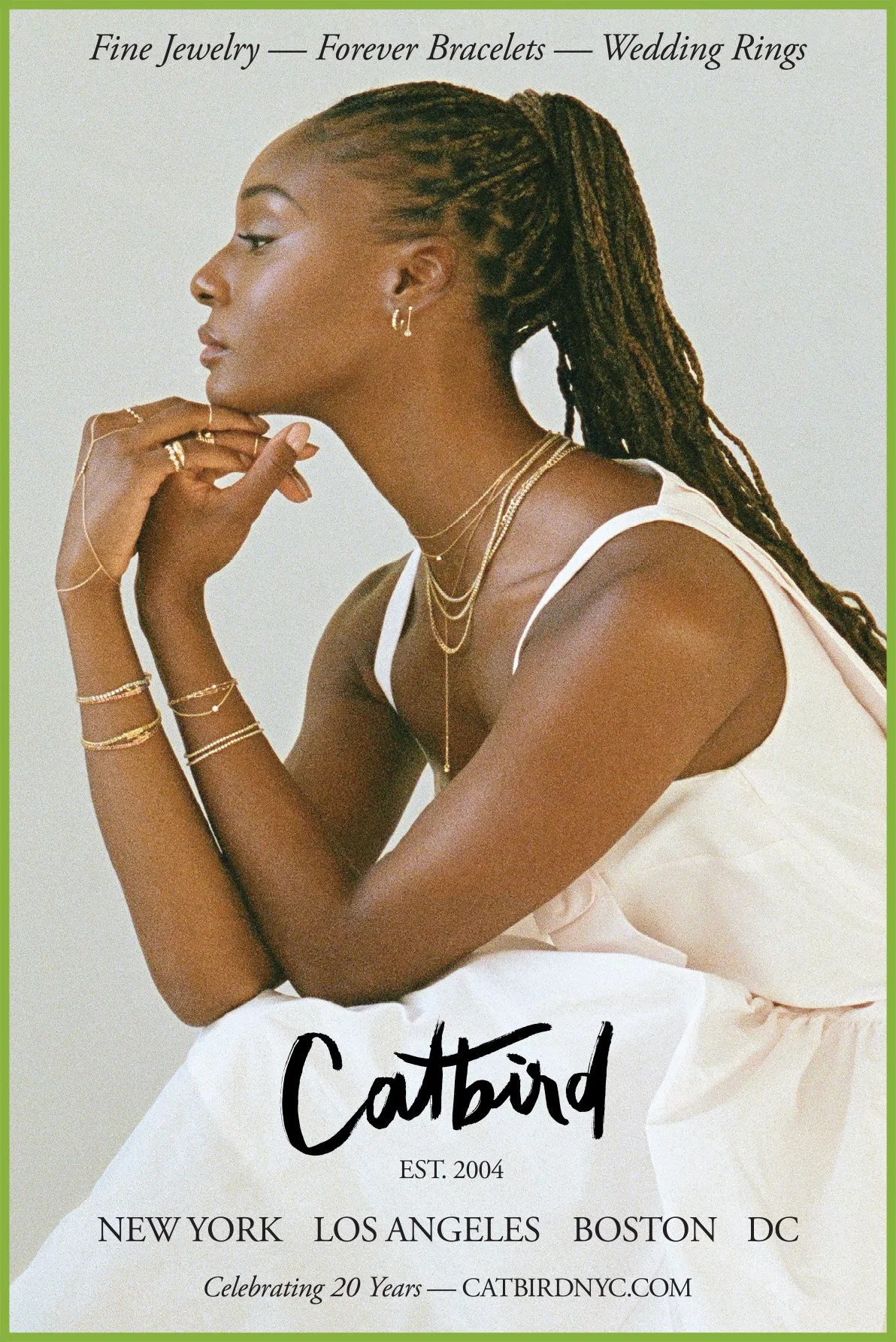 A woman with dreadlocks wearing jewelry, a white top, and a cream-colored dress, sitting in profile with her chin resting on her hands, surrounded by text about jewelry, bracelets, wedding rings, and the brand Catbird established in 2004.