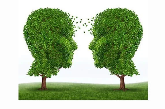 Two trees with foliage shaped like human profiles facing each other, with leaves forming faces and a few leaves floating between them.