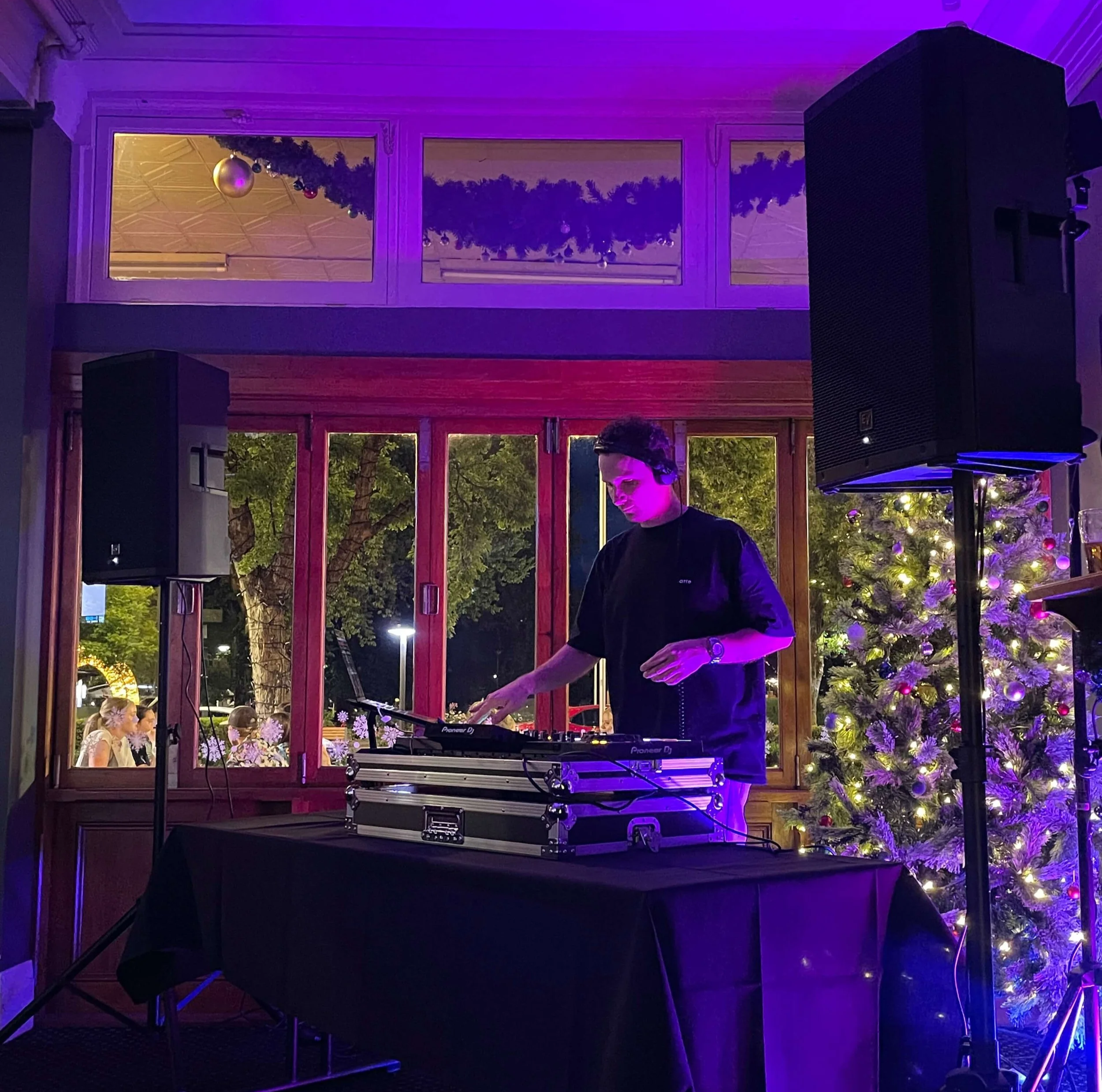 A DJ wearing headphones plays electronic music on a DJ controller in a pub in Orange, NSW. The DJ plays Party Classics, House and Disco.