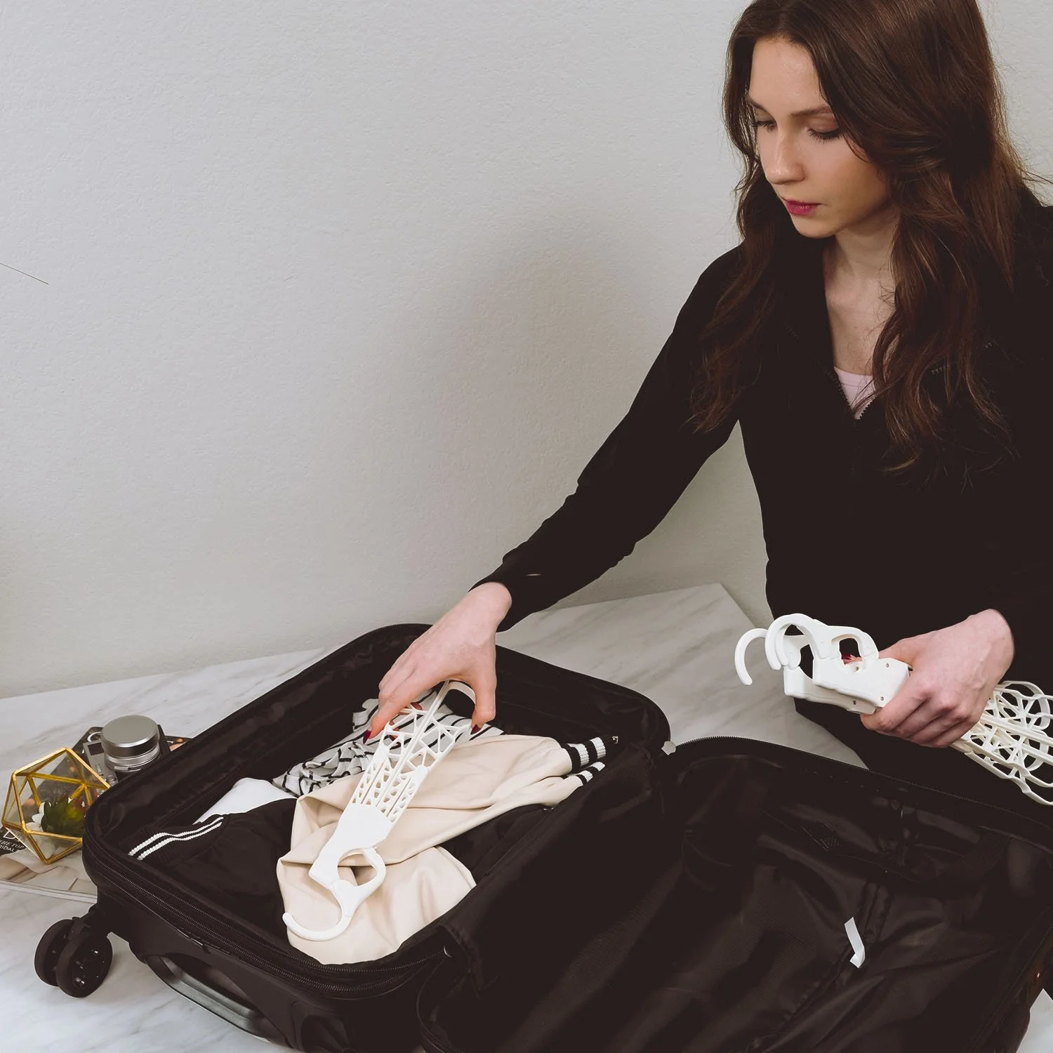 A woman packing a suitcase with hanging organizers and clothing.
