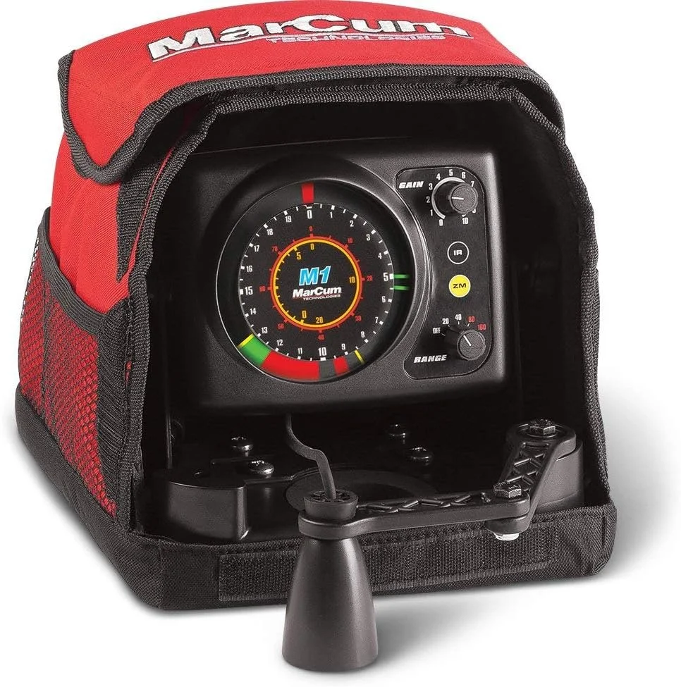 A racing simulation device resembling a digital dashboard with gauges and controls, mounted on a black stand inside a red and black carrying case labeled "Marshi" in white and red. The device features a round gauge with a digital display, multiple buttons, and a small joystick.
