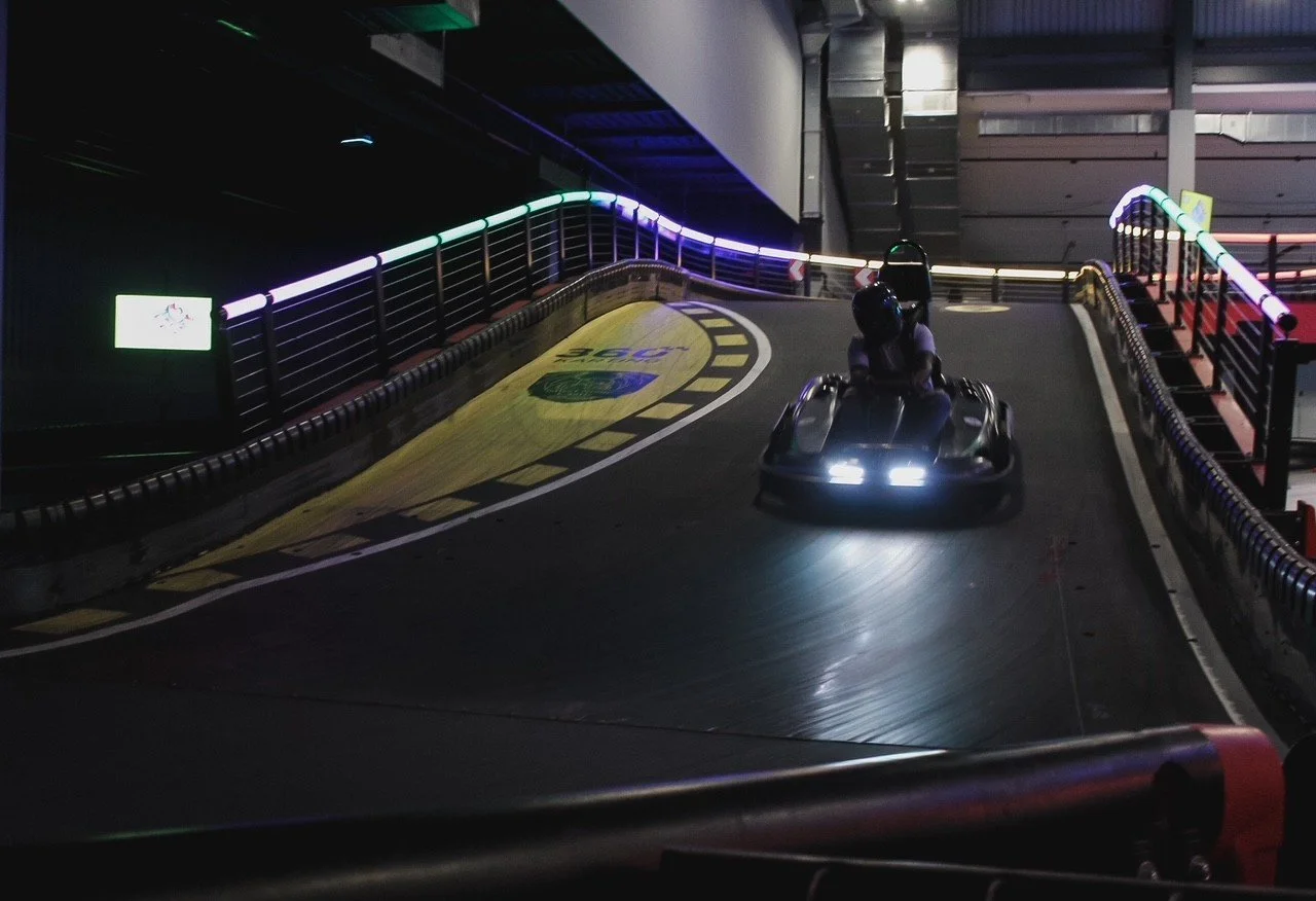 Go-kart climbing the neon-lit ramp of the indoor track at Silver Stone Castle in Swansea, MA