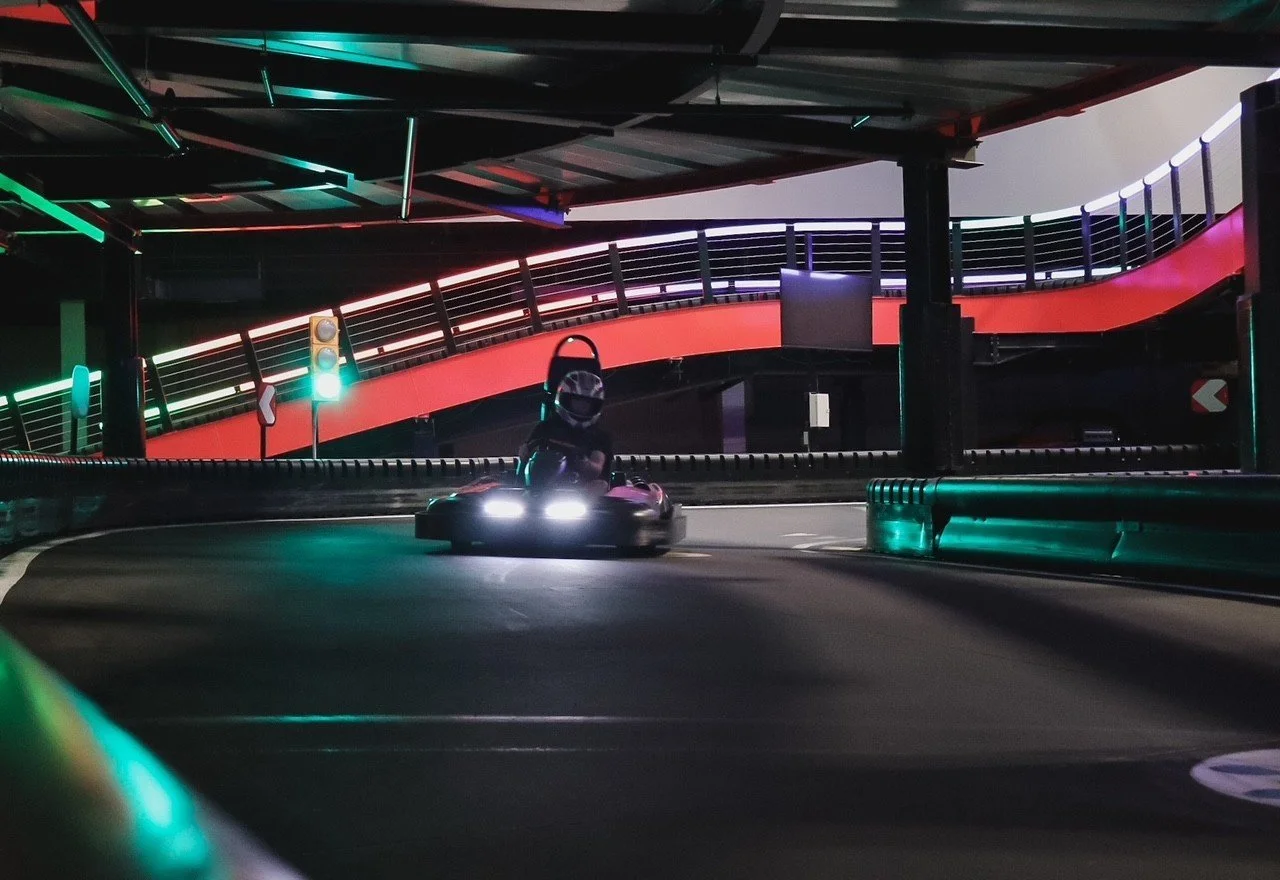 Electric go-kart rounding a banked turn on the indoor multi-level track at Silver Stone Castle, Swansea, MA