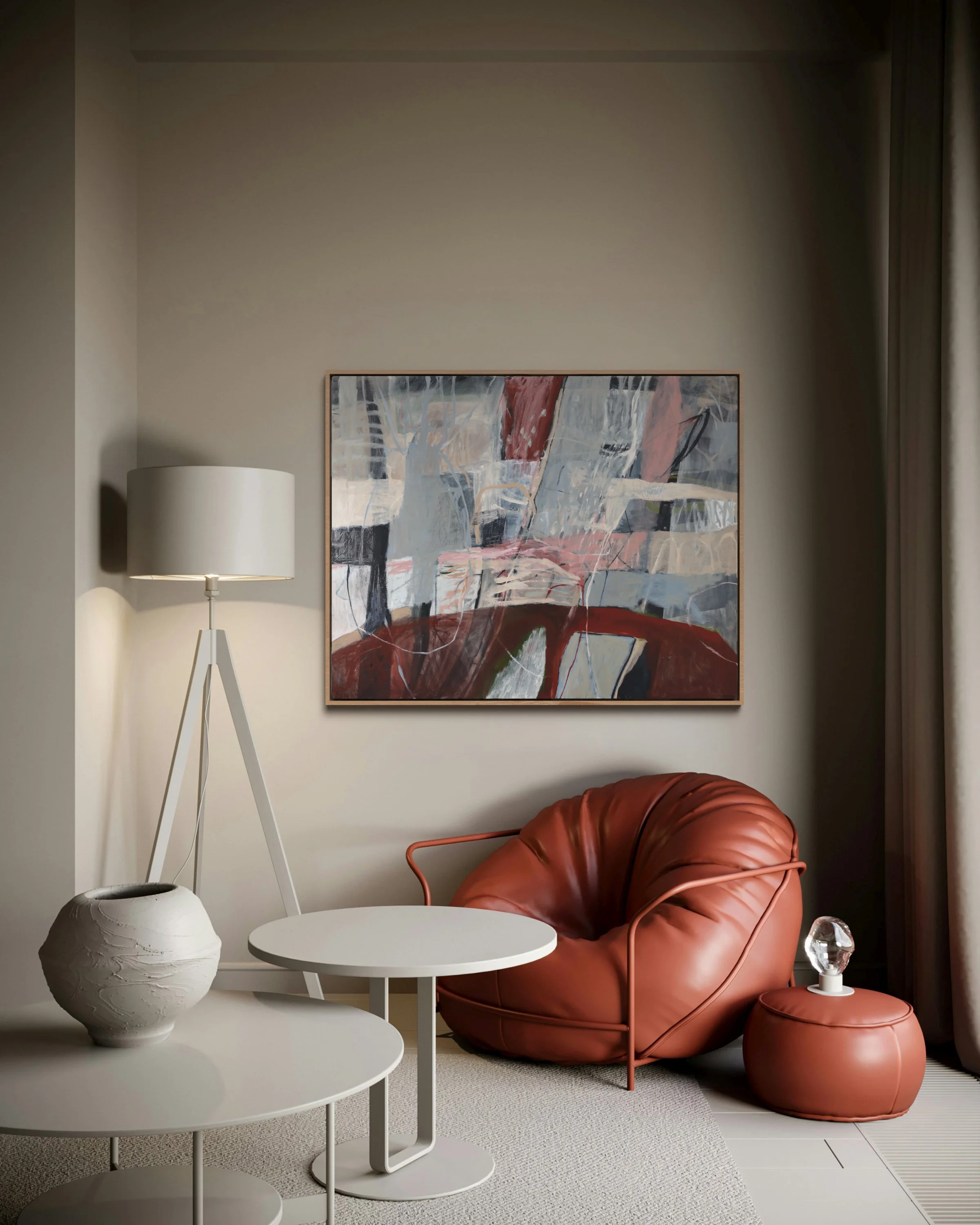 A modern living room corner featuring a white three-tier side table with a textured white ceramic vase, a tall white floor lamp with a round shade, an abstract painting with splashes of red, gray, black, and white on the wall, a rust-colored leather 