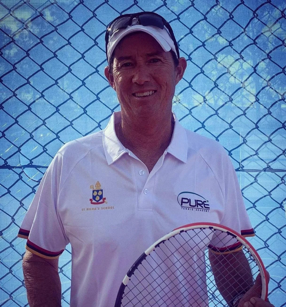 A man holding a tennis racket standing in front of a chain-link fence