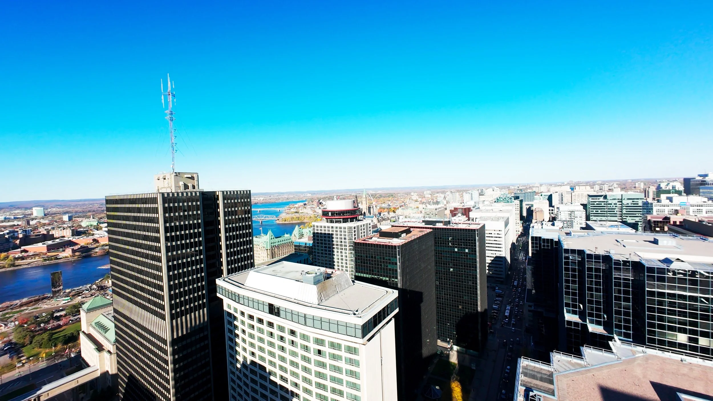 Aerial view of a city skyline with tall skyscrapers, a river, and a clear blue sky.