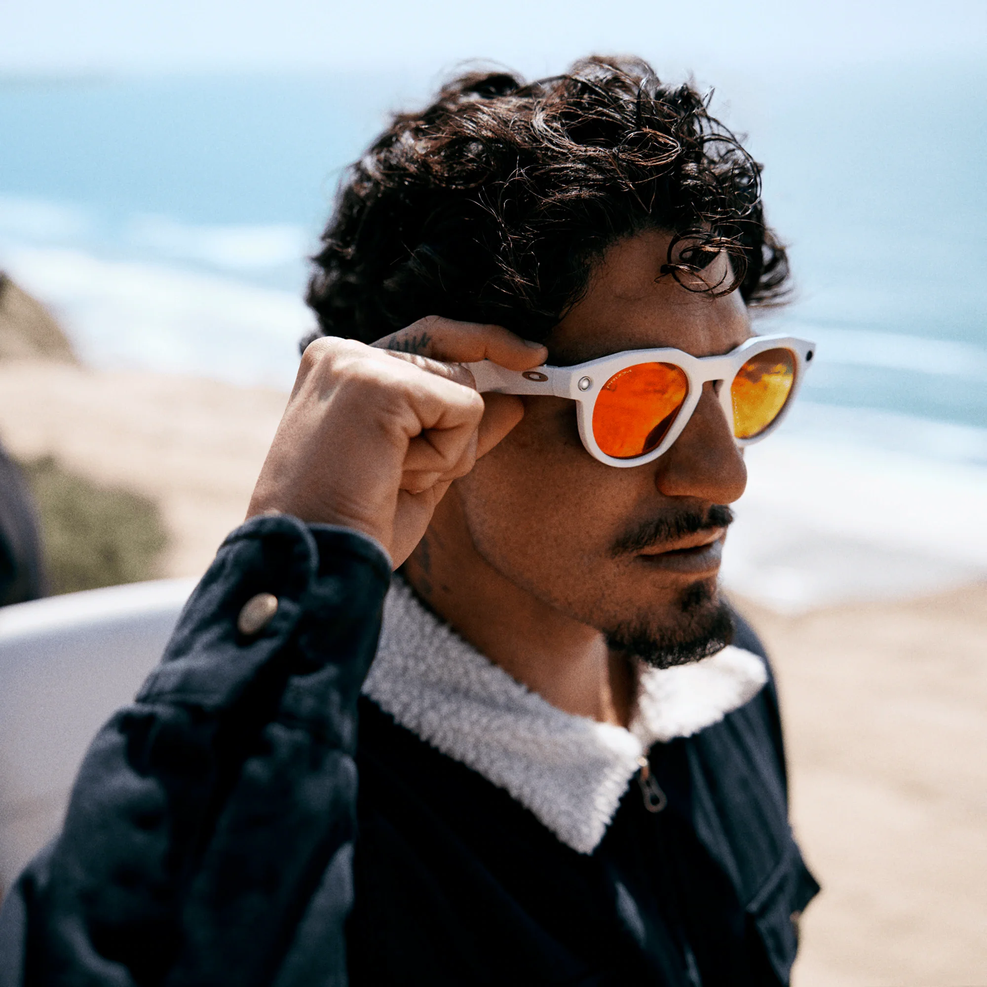 Model wearing white Oakley Meta HSTN glasses with orange lenses