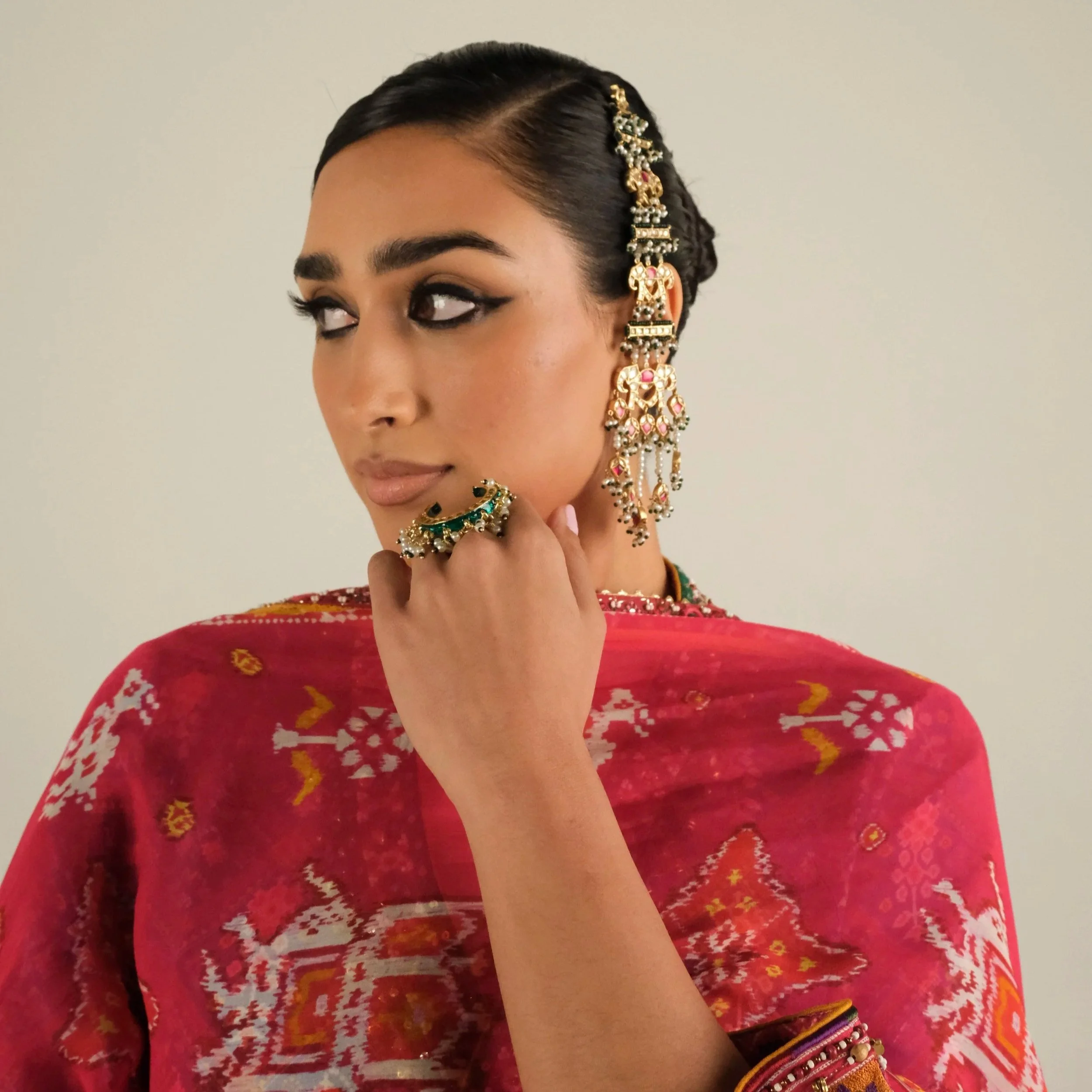 Woman in traditional Indian attire with jewelry, looking to the side.