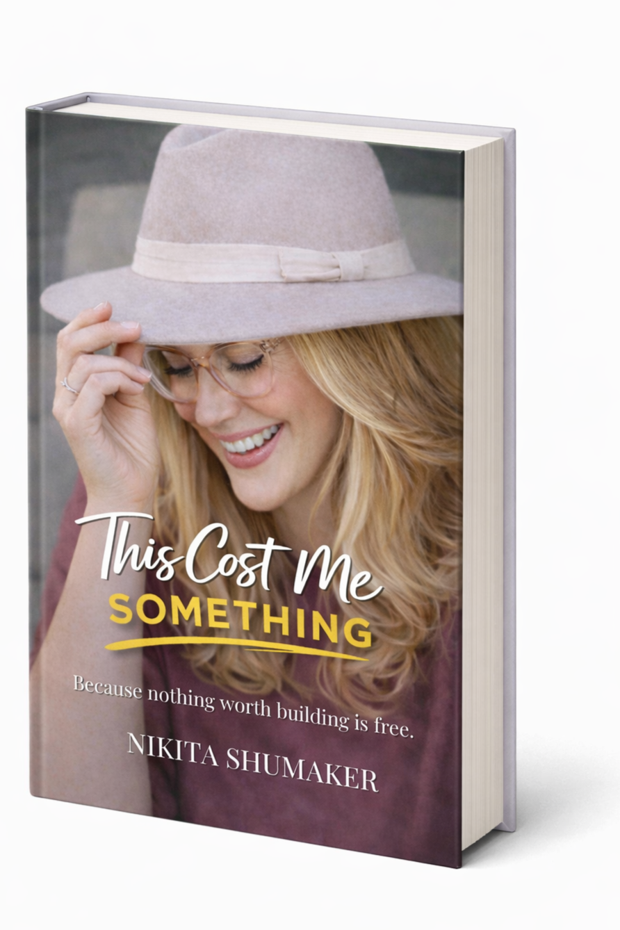 A book titled "This Cost Me Something" featuring a smiling woman with blonde hair, glasses, and a beige hat on its cover.