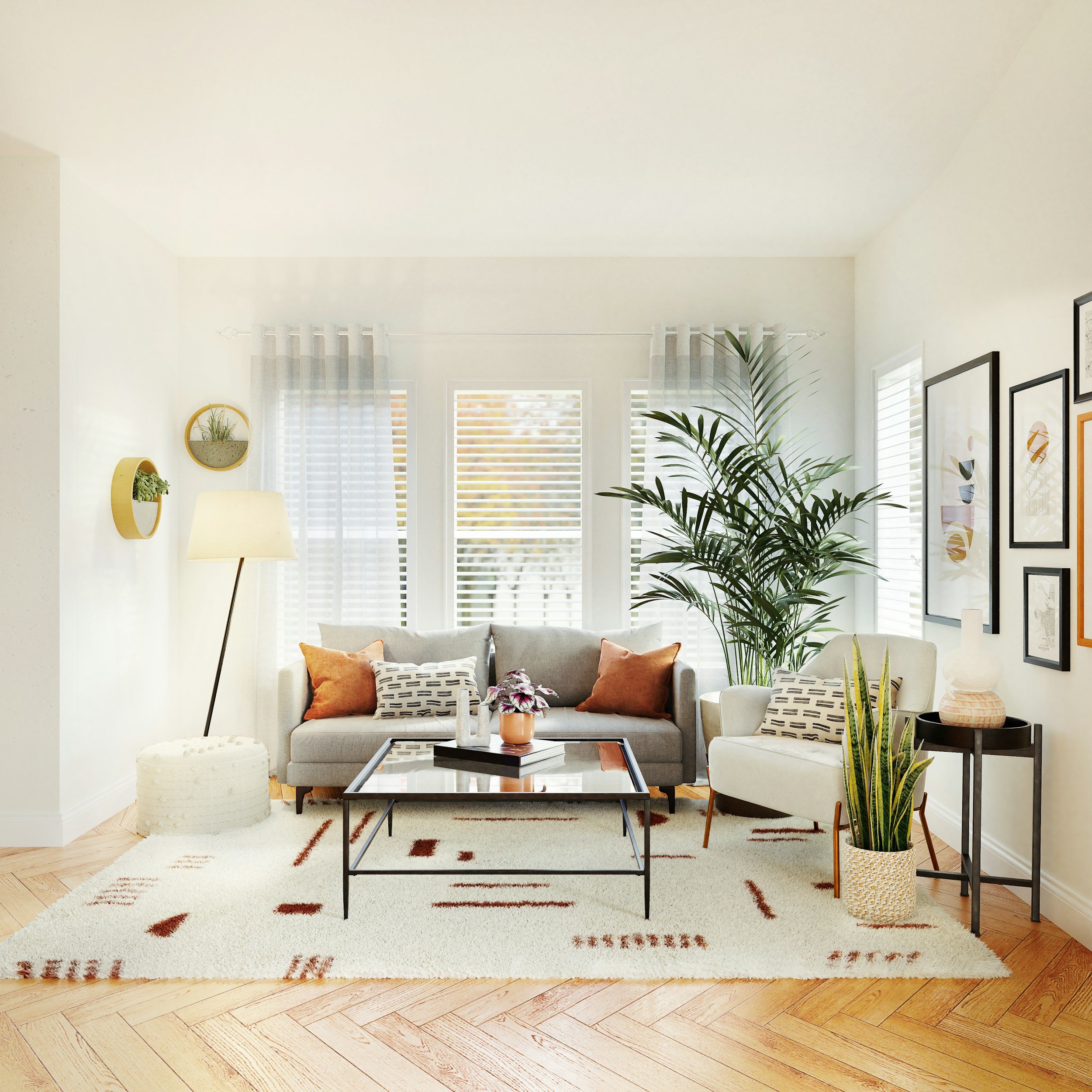 Bright living room with white walls, large windows with blinds, beige sofa with orange and patterned cushions, white armchair, glass coffee table with plants and books, large green plant, wall art, and a patterned rug.