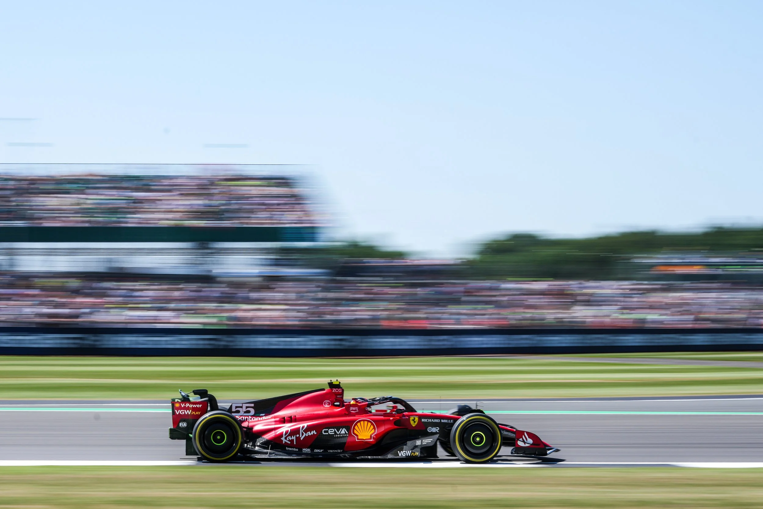 A red Formula 1 race car speeding on a racetrack with blurred spectators and background.