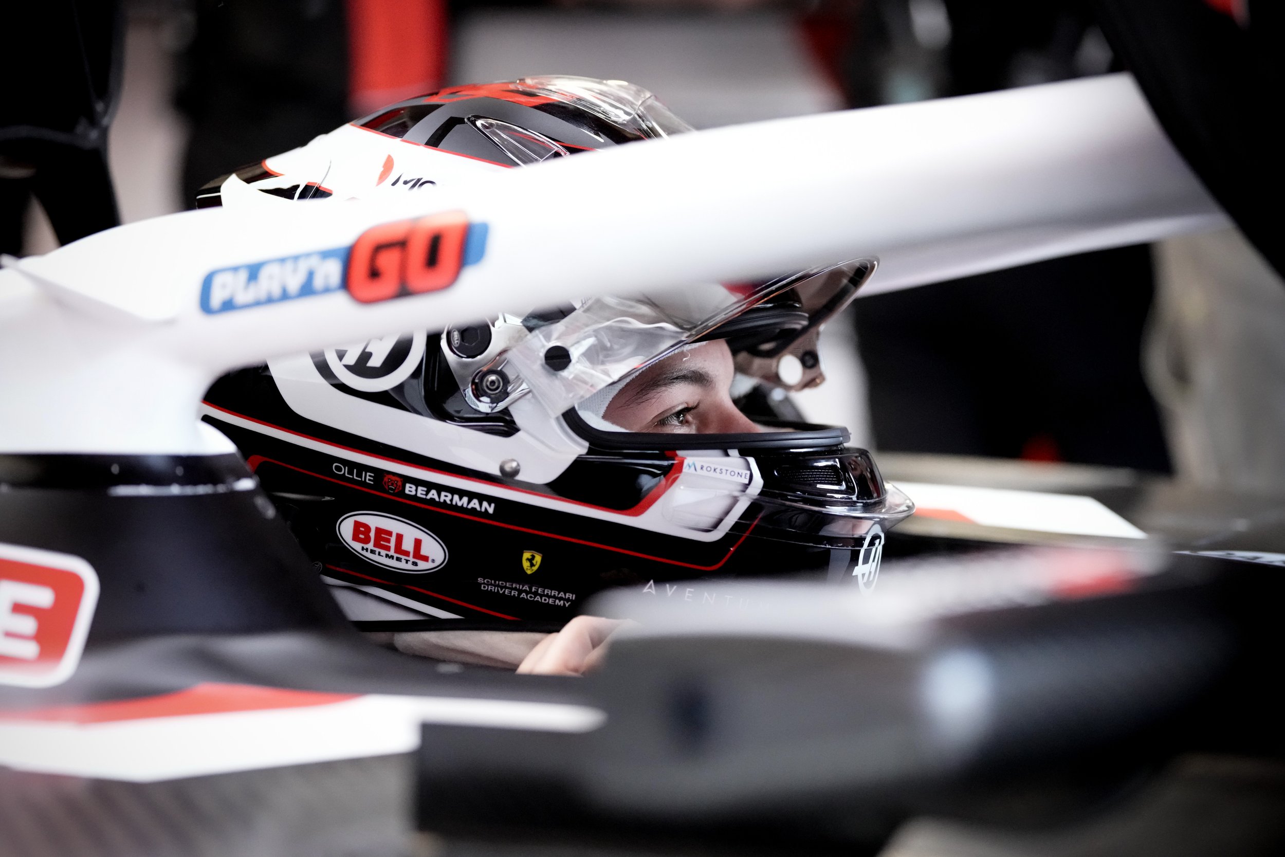 Close-up of a race car driver wearing a helmet, seated in a race car, ready to race.