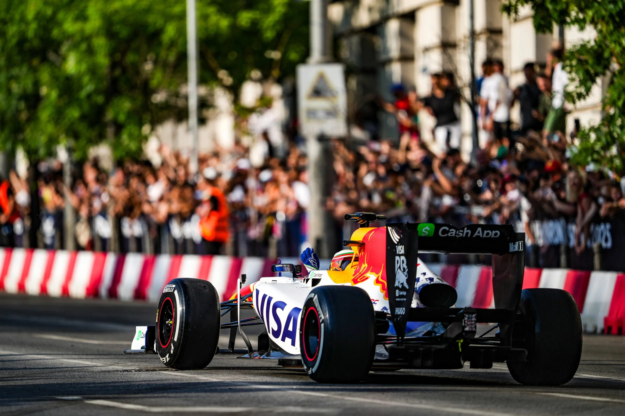 A Formula 1 race car on a city street track with a crowd of spectators in the background.