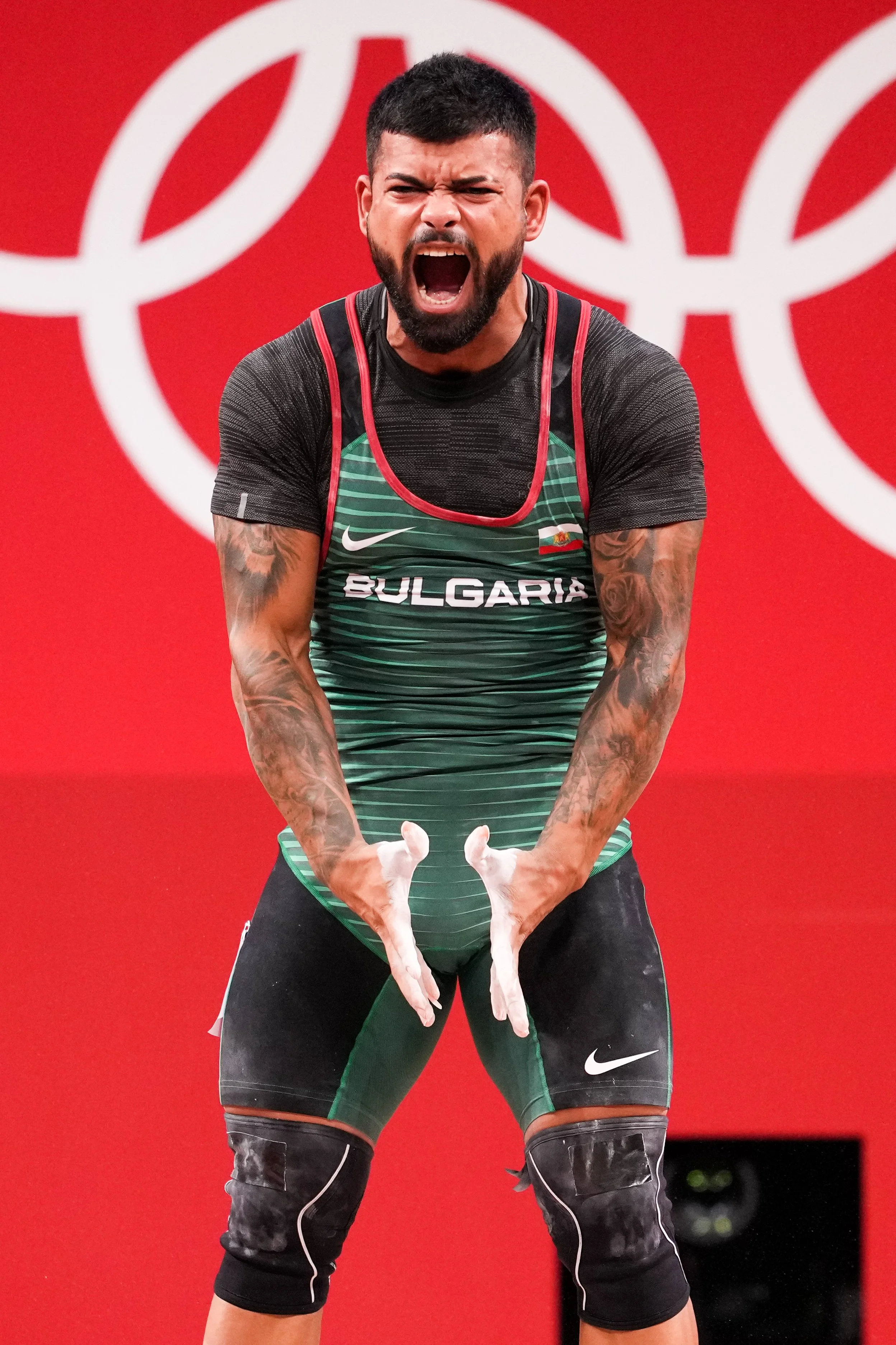 A male athlete from Bulgaria, wearing athletic gear, cheering passionately during a sports event against a red background.