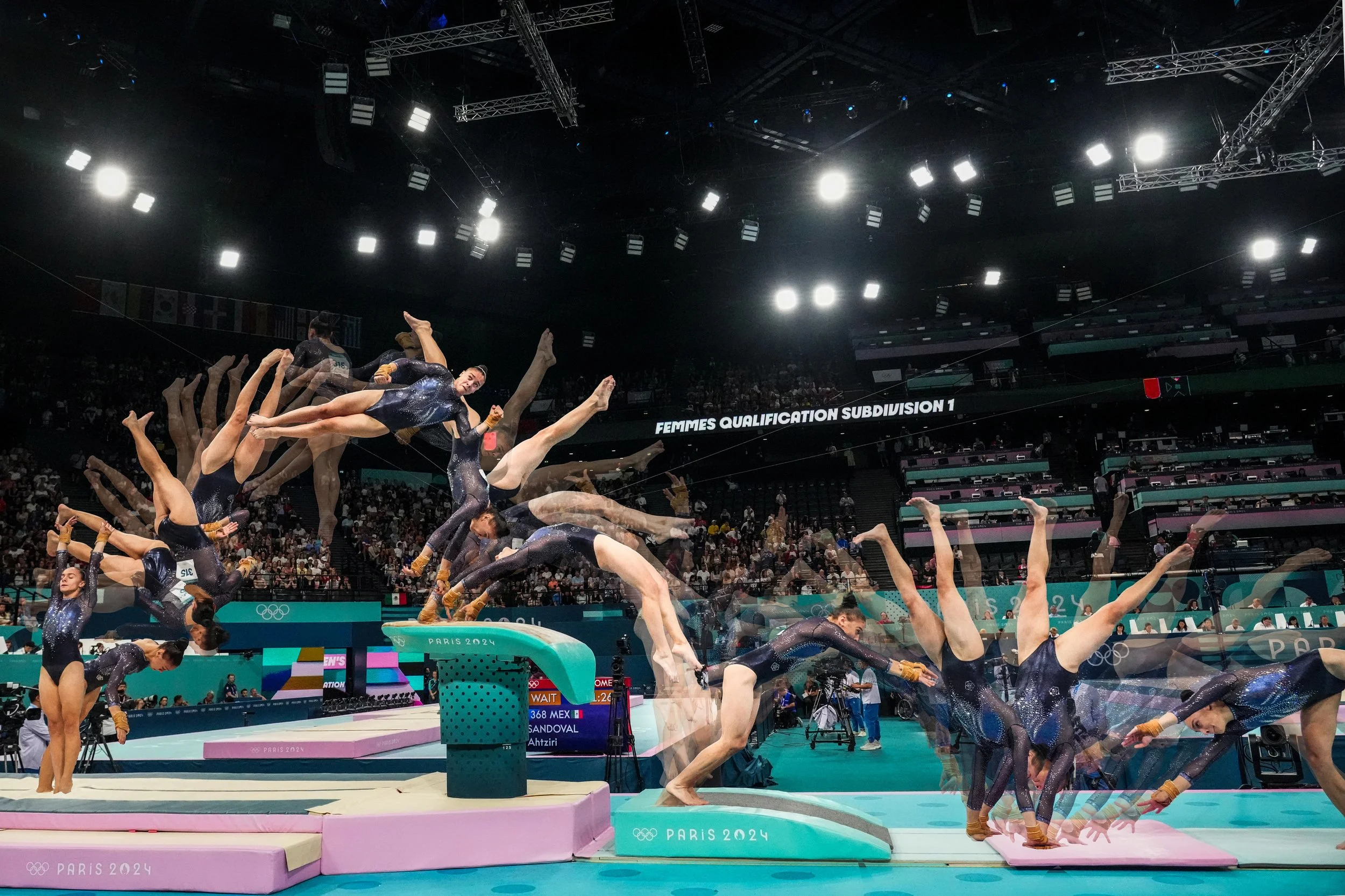 Multiple female gymnasts performing a synchronized routine on the uneven bars and floor exercise during the Paris 2024 Olympics gymnastics event, with a large audience and bright arena lights in the background.