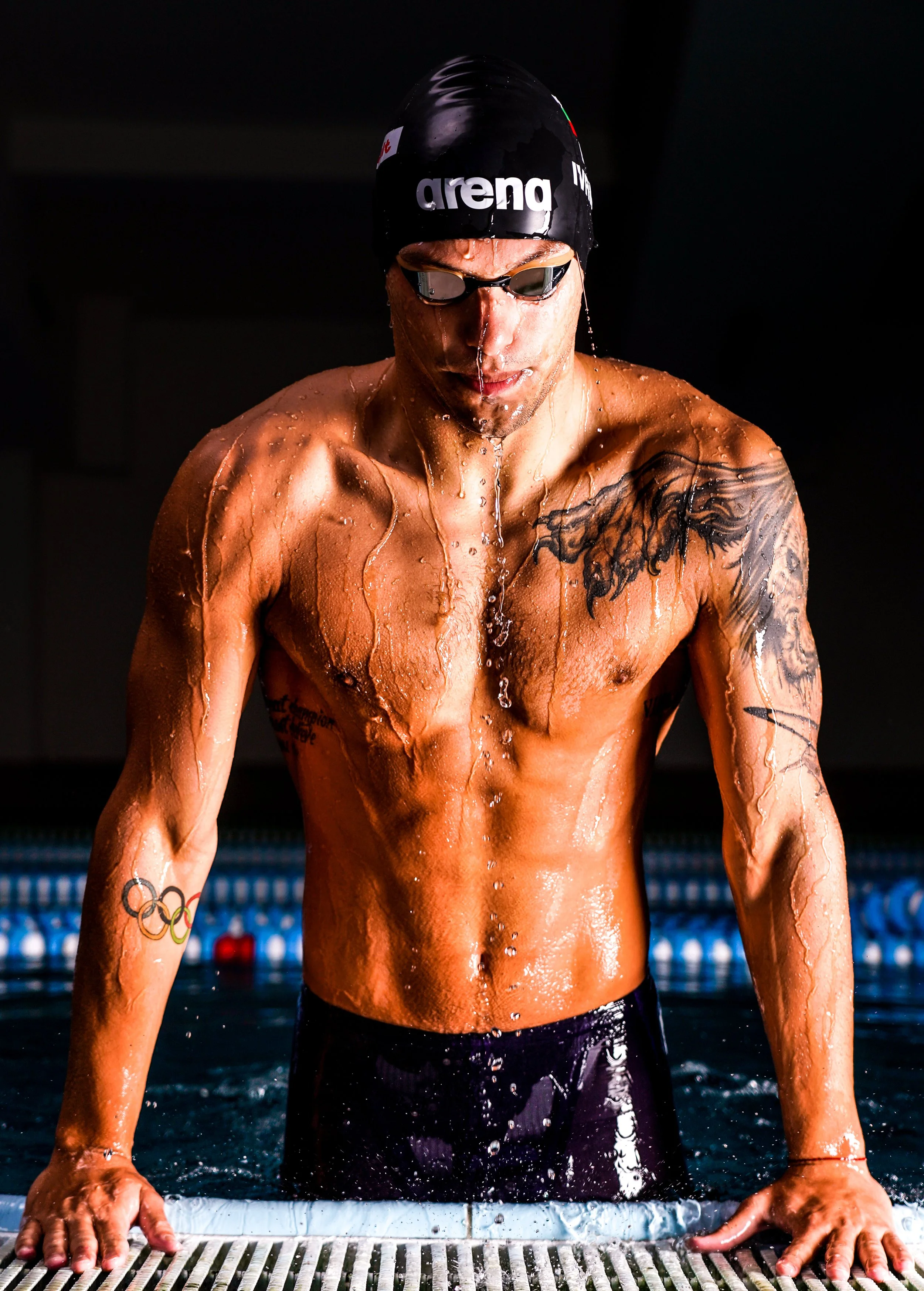 Swimmer in a black swim cap and goggles, drying off after a swim in the pool.