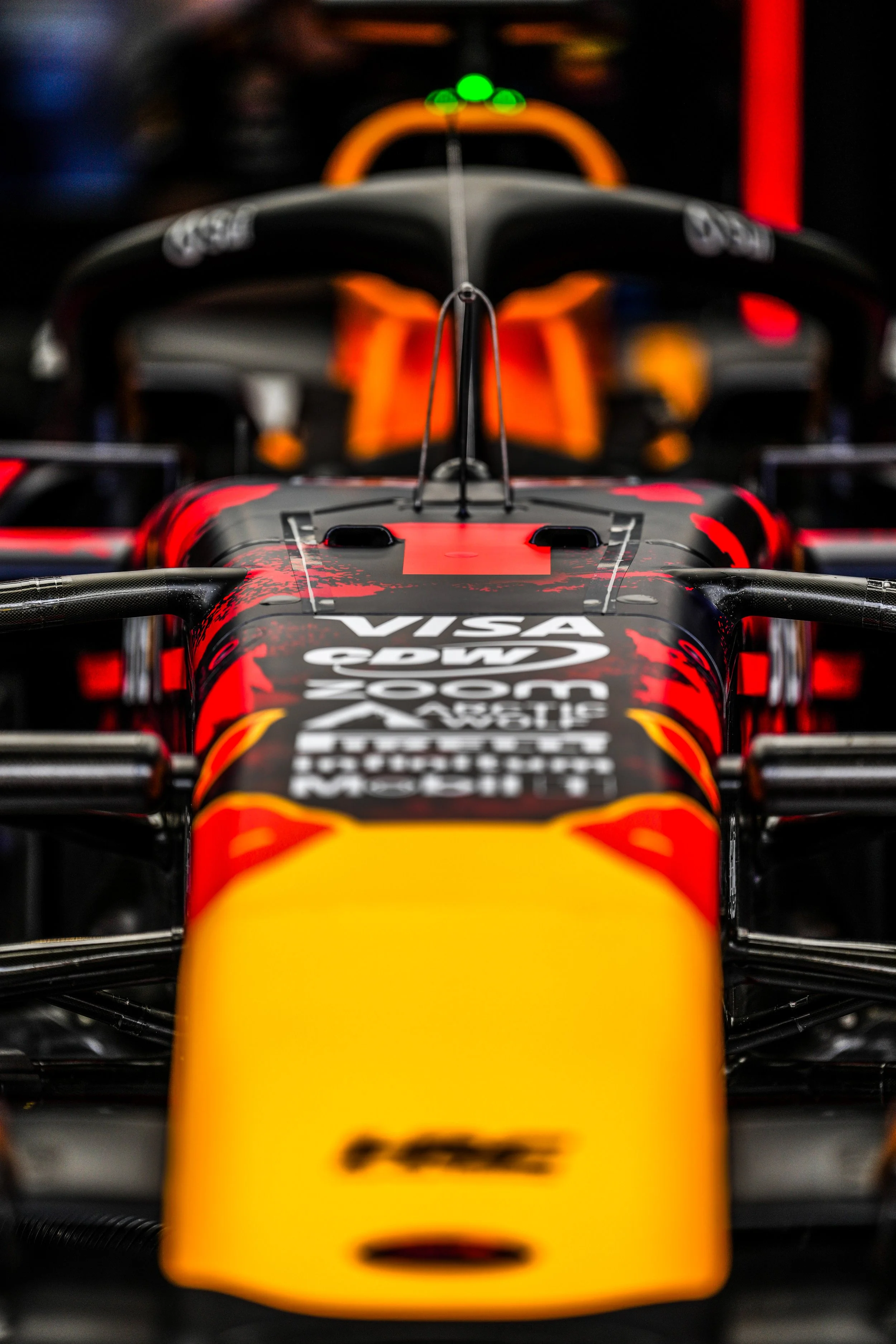 Close-up of a Red Bull Racing Formula 1 car in a garage, showing the front nose and aerodynamics with various sponsor logos.