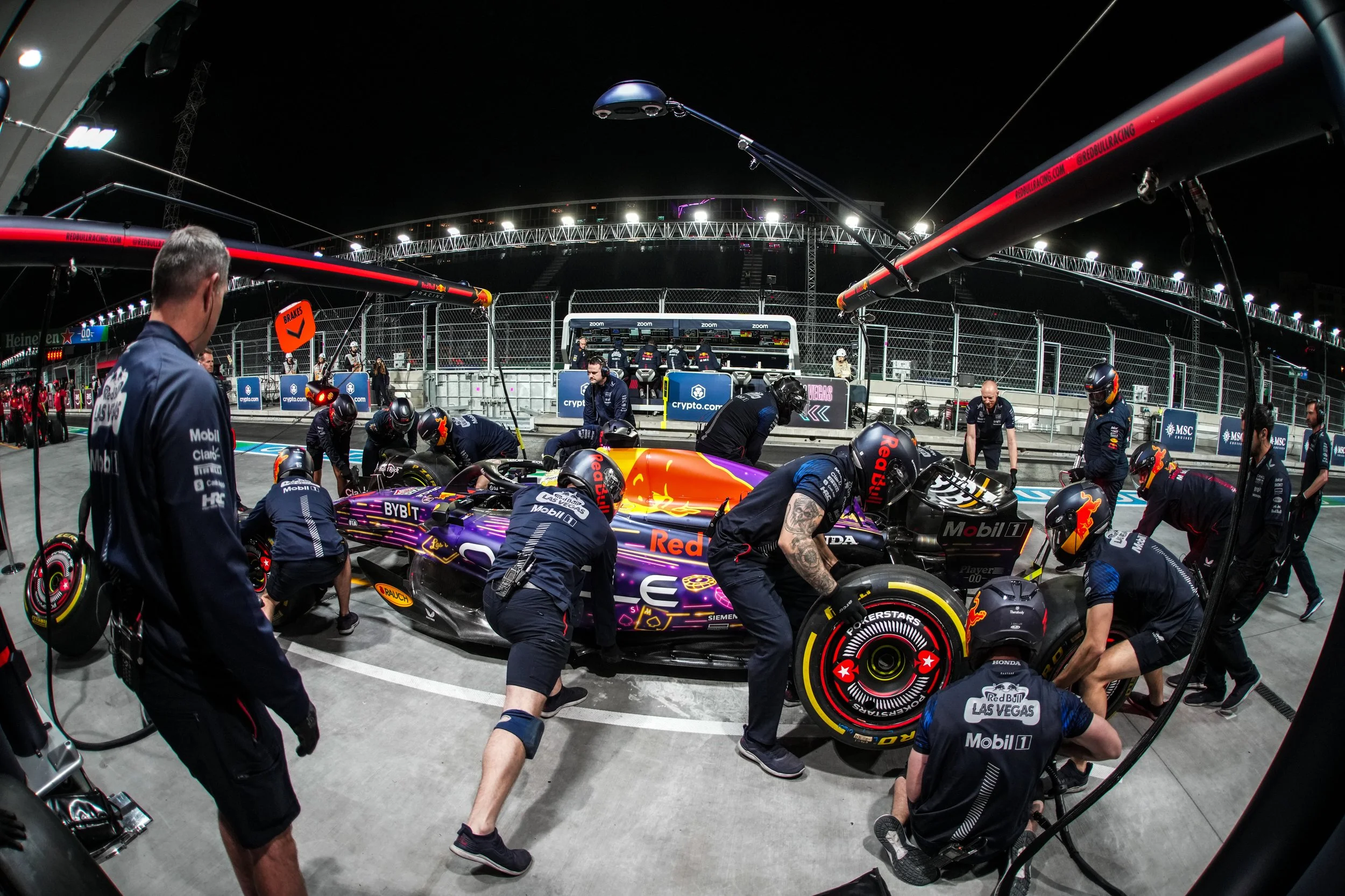 Formula 1 car in the pit stop with team members working on it at night during a race.