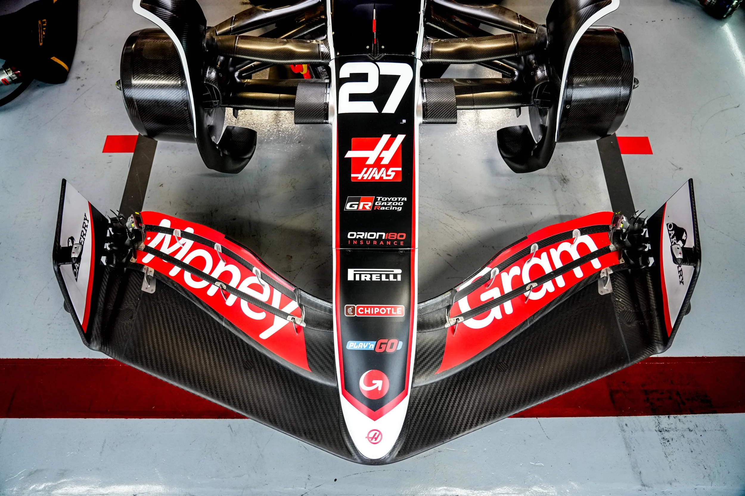 Top view of a race car's front section, featuring prominent branding from Monster Energy, Garmin, and other sponsors, with carbon fiber aerodynamic components.