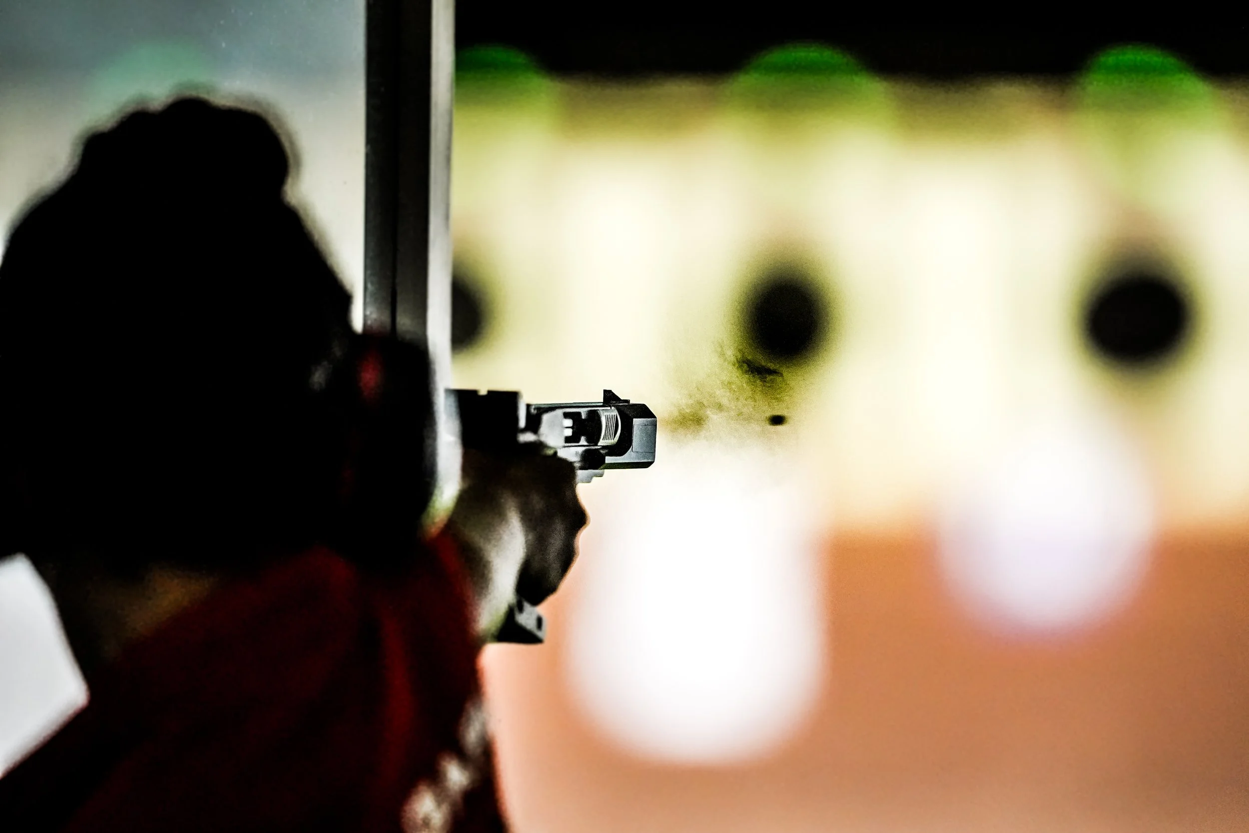 Person aiming a handgun at a shooting range, with targets in the background.