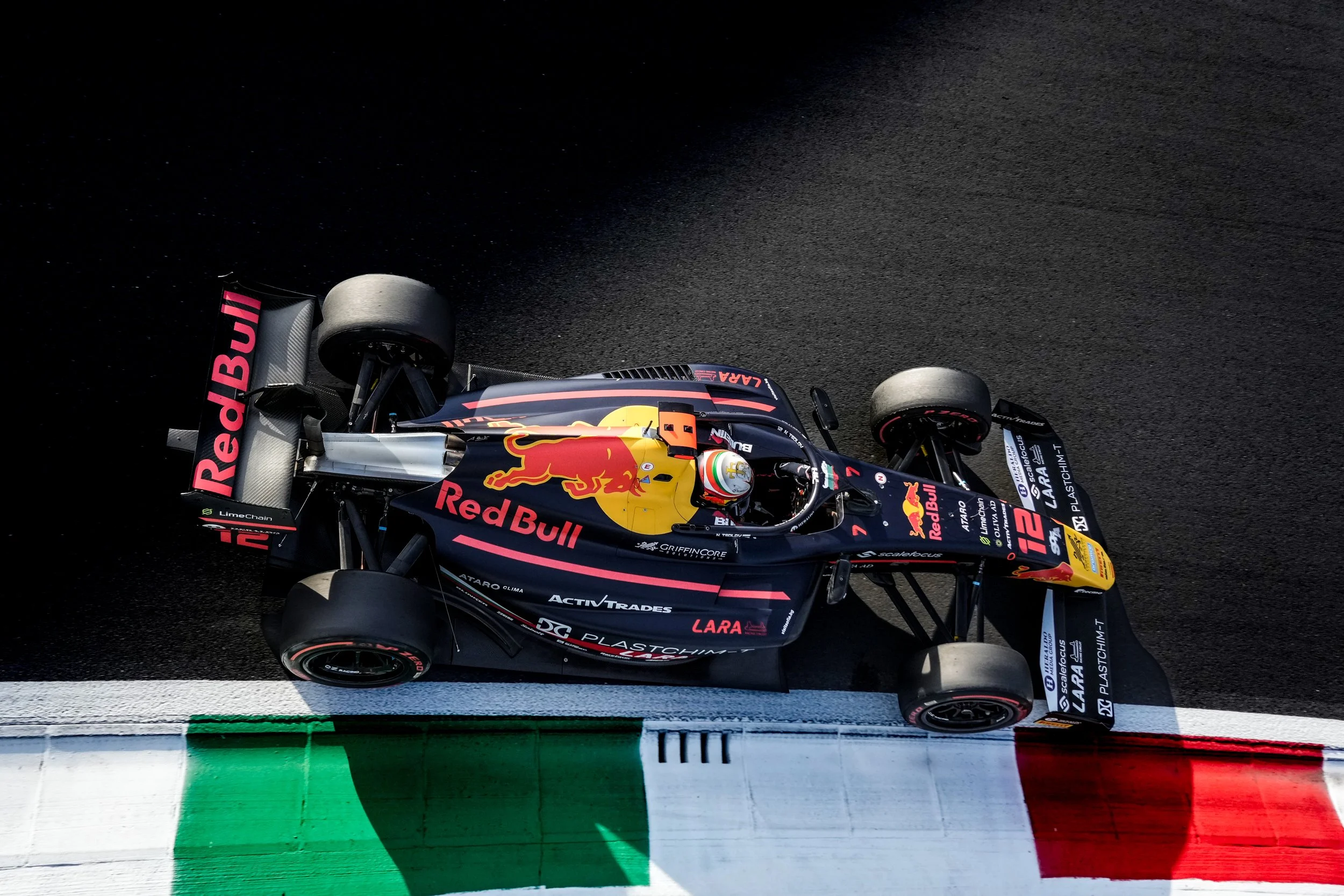 Race car on track with Red Bull logos and patriotic Italian colors painted on curb.