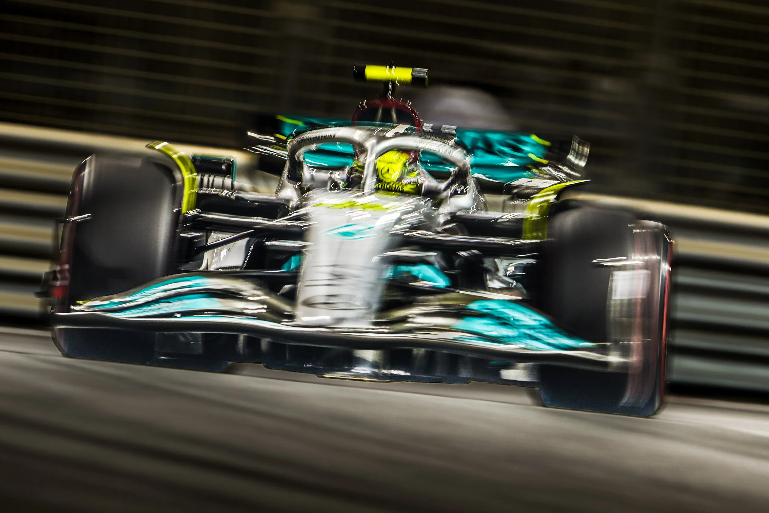 A Mercedes Formula 1 car racing at high speed on a track at night.